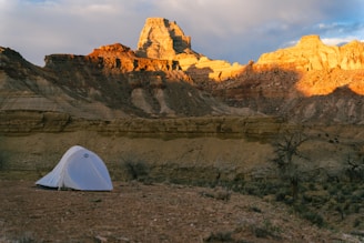 White tent set up in a desert landscape at sunset.