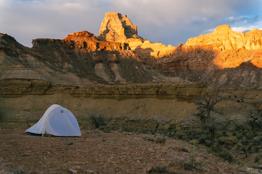 White tent set up in a desert landscape at sunset.