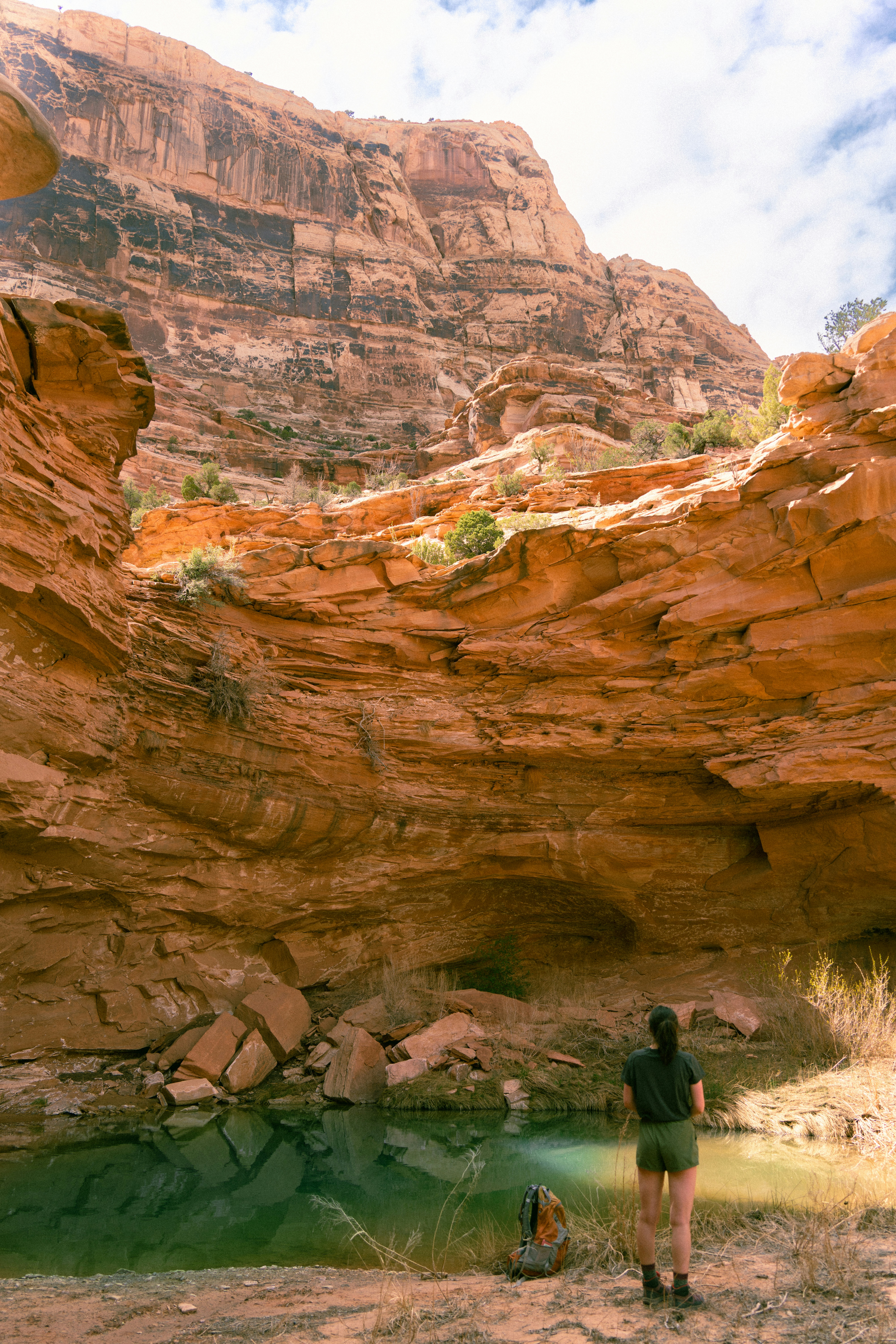 Woman looking at a pool in a desert canyon.