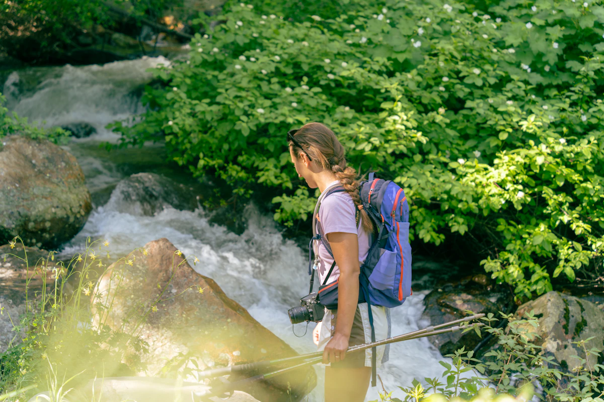Hiker carrying a backpack beside a mountain stream