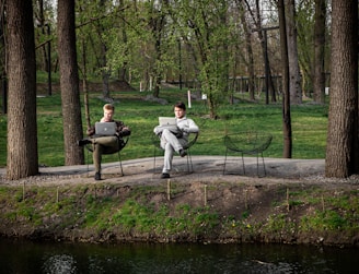 Two men working on laptops in a park