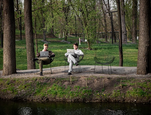Two men working on laptops in a park