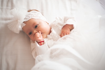 A baby girl in a white dress and headband