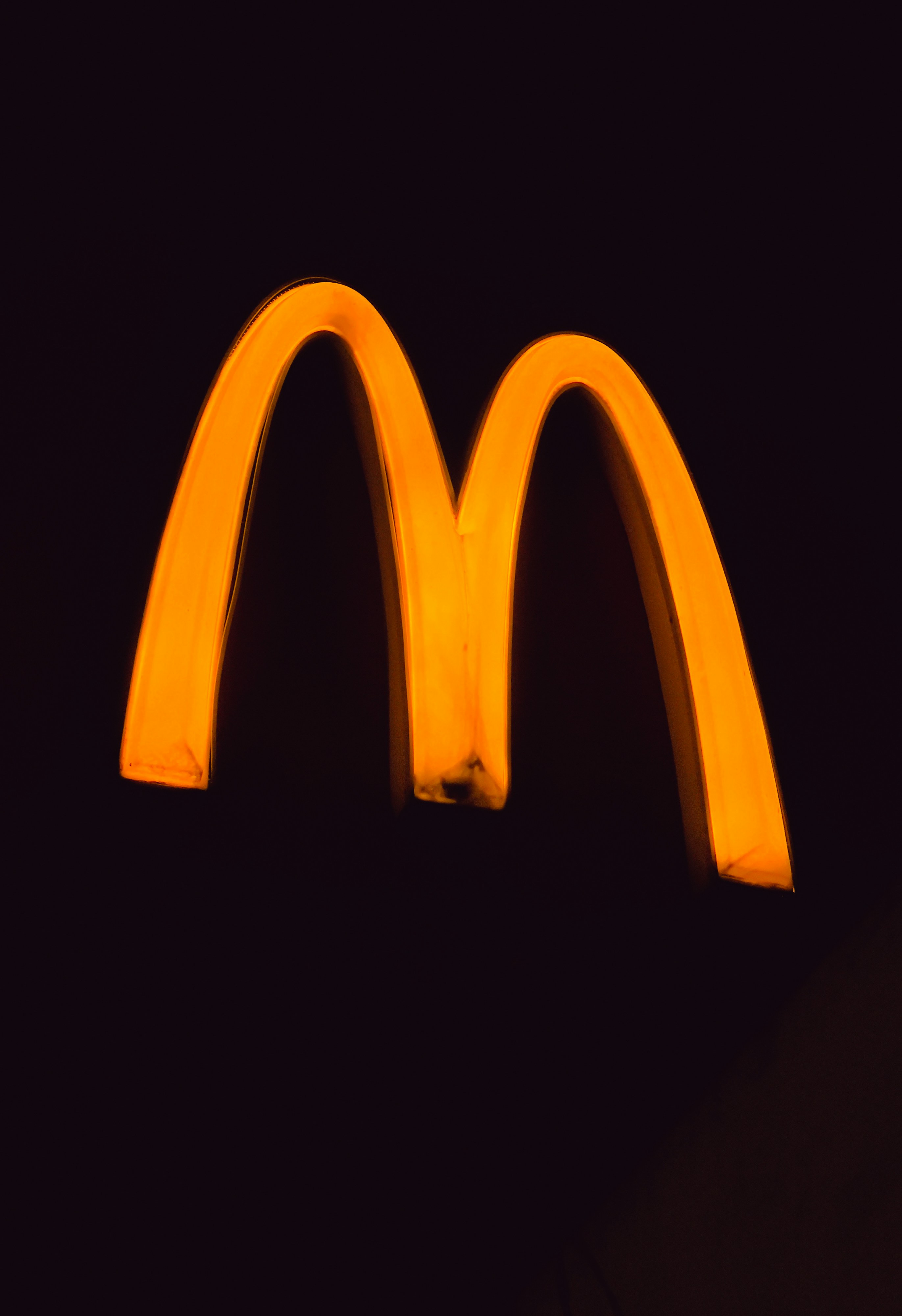 Golden mcdonald's arches illuminated against dark background