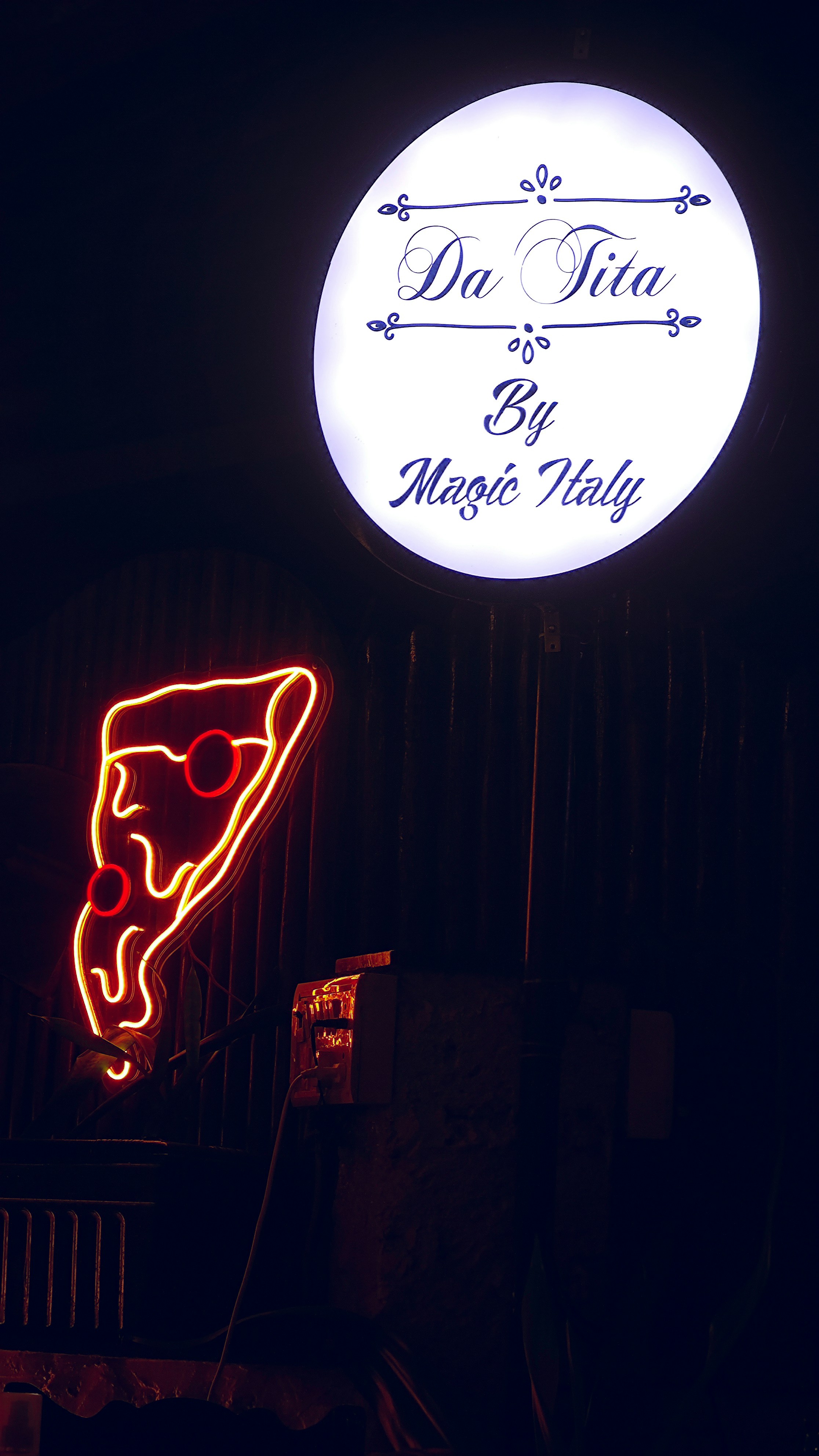 Neon pizza slice and illuminated sign at night