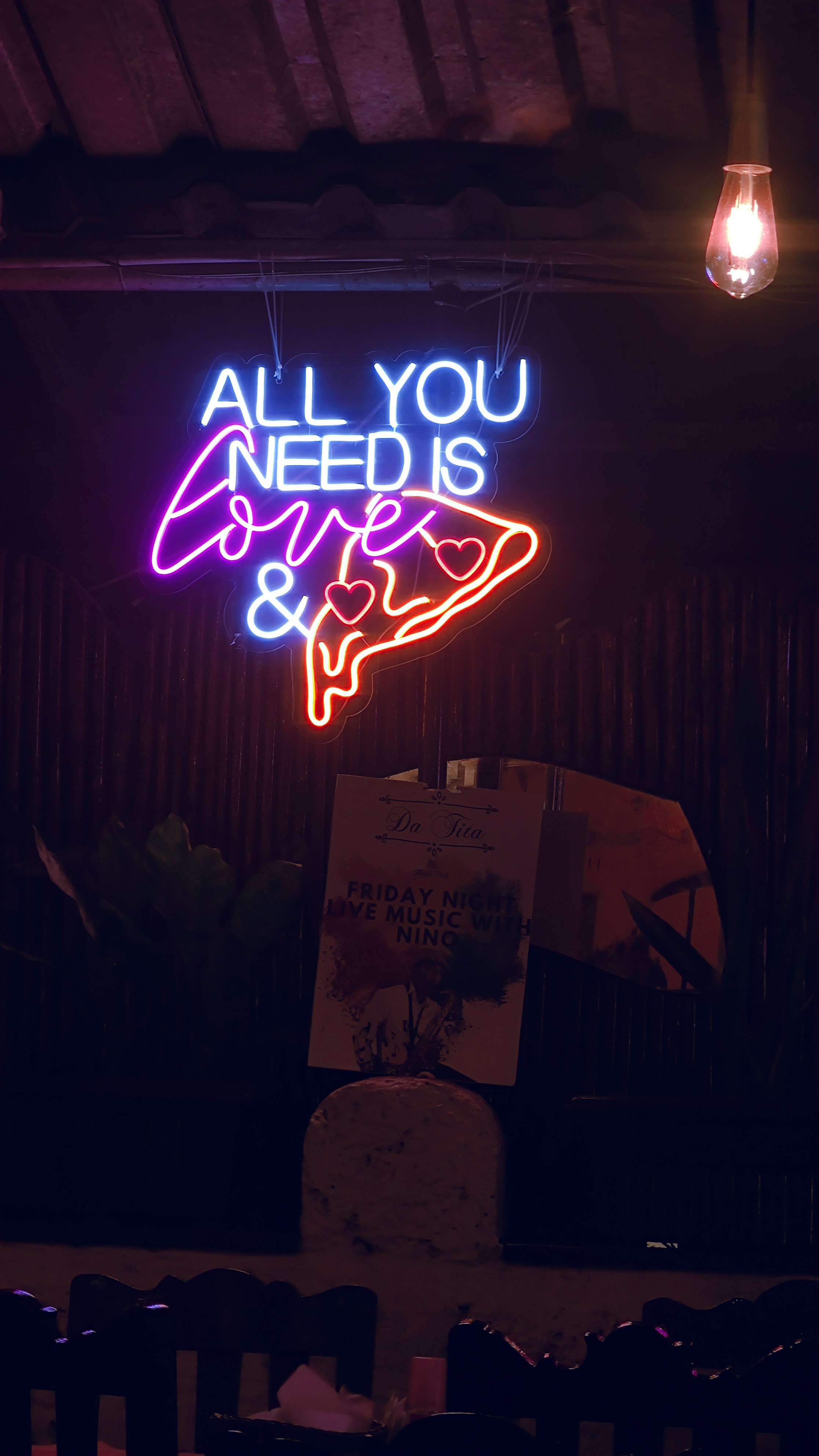 Neon sign says "all you need is love & pizza"