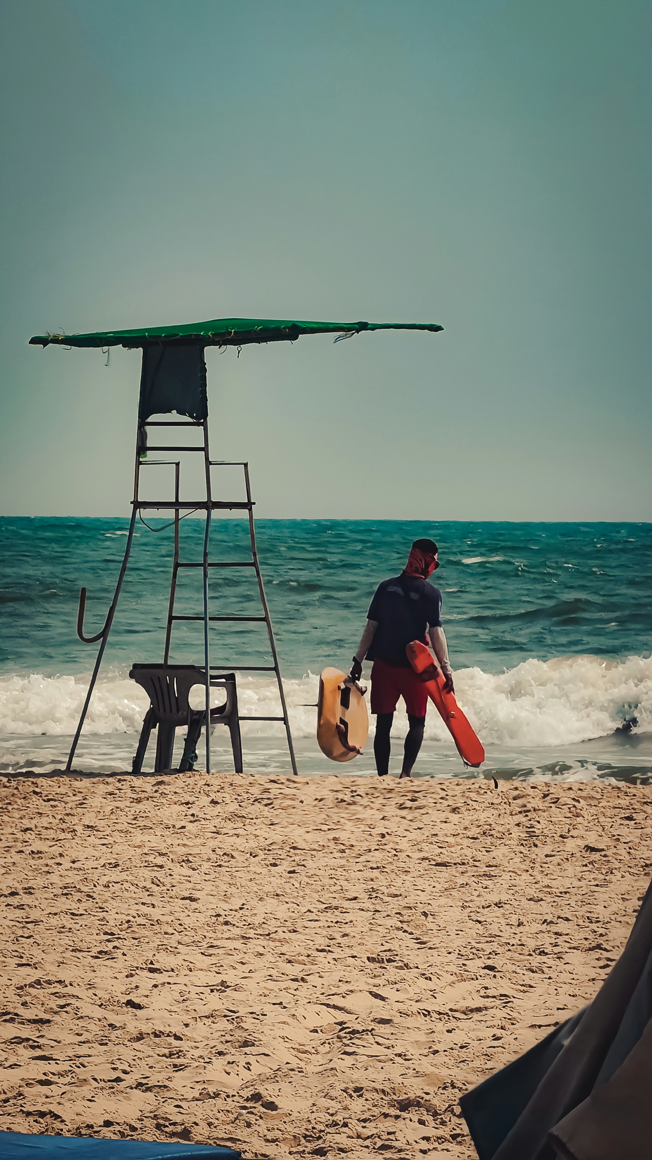 Lifeguard stands by the ocean with rescue equipment.