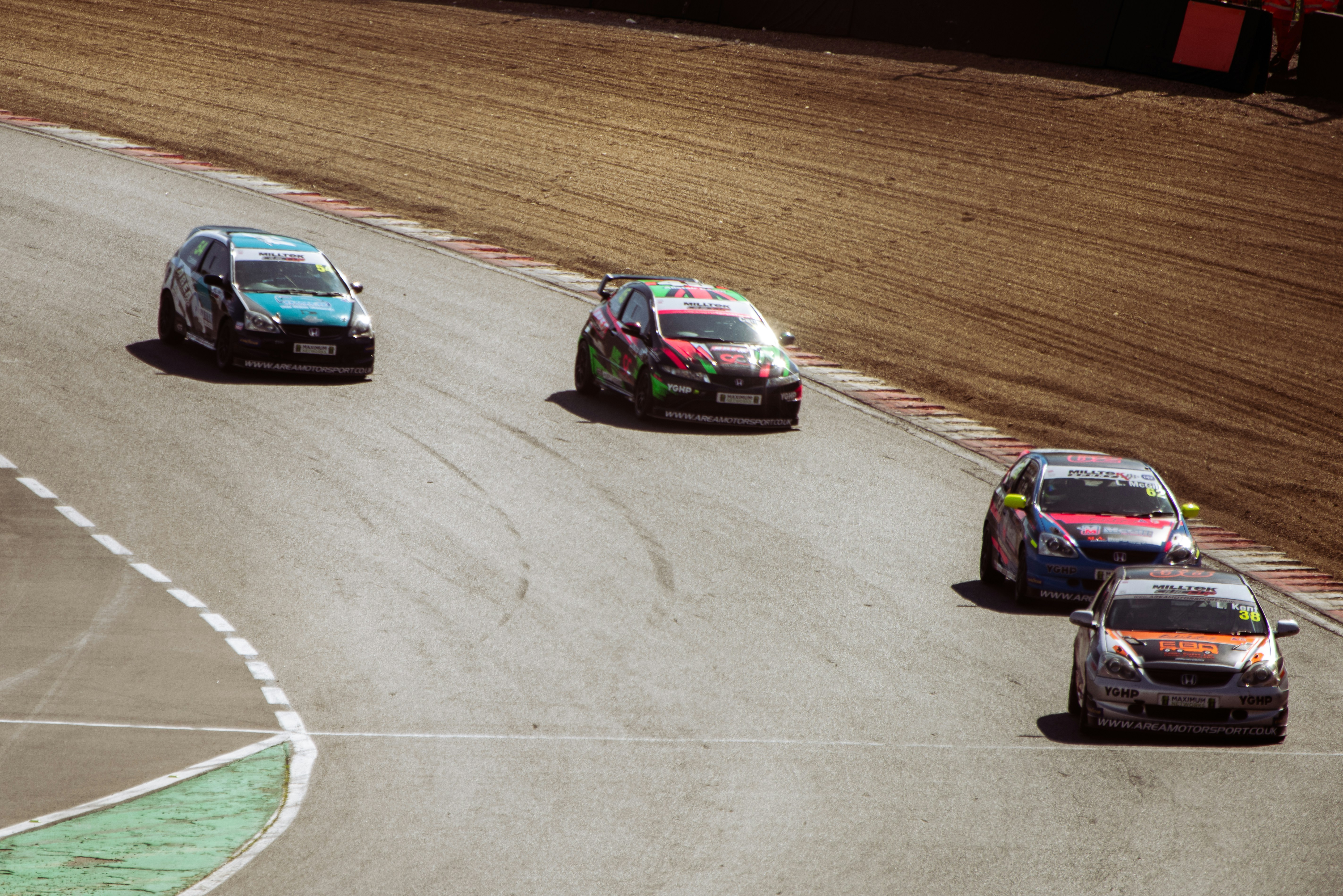 Race cars speed around a dirt track corner.