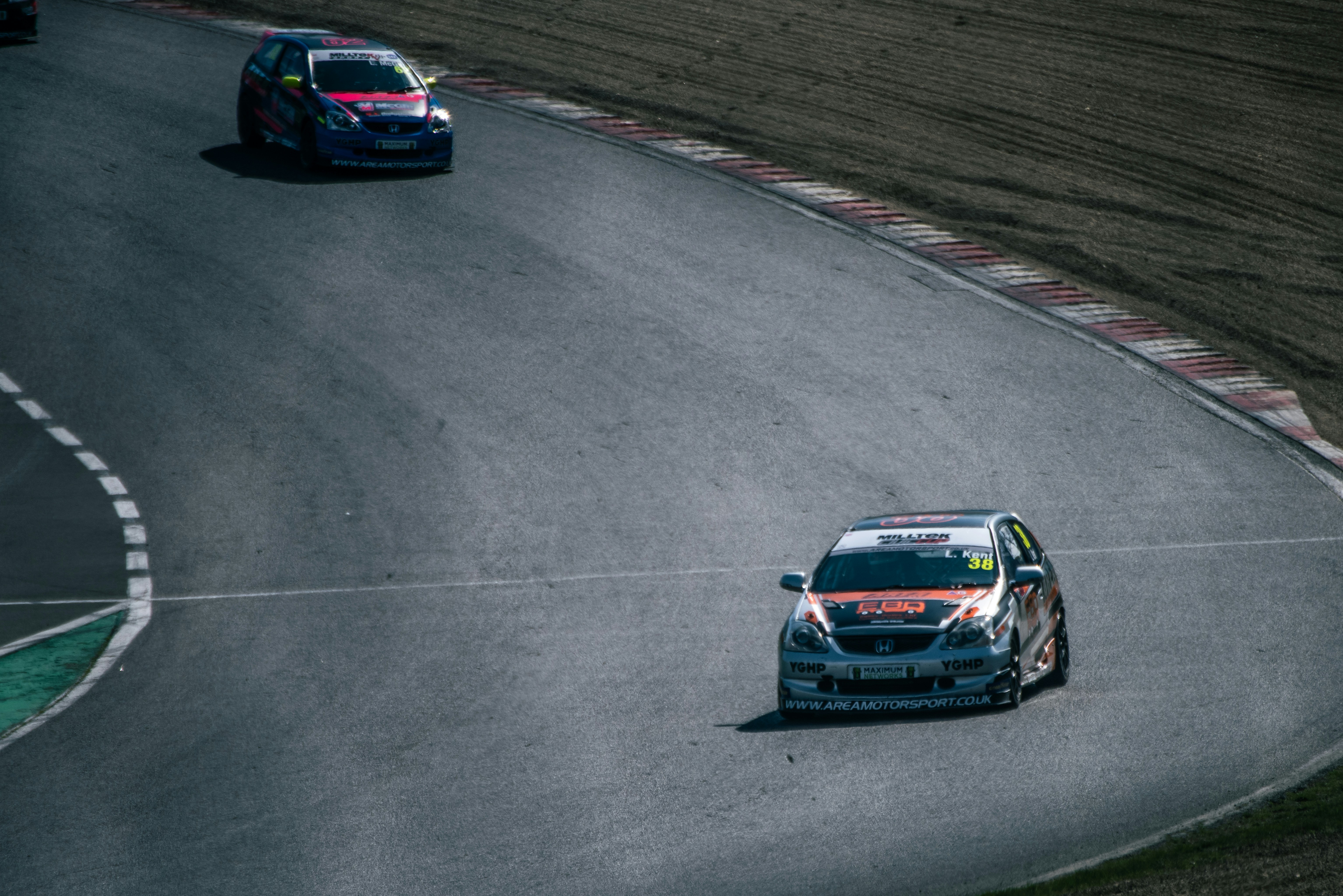 Race cars speeding on a winding asphalt track.