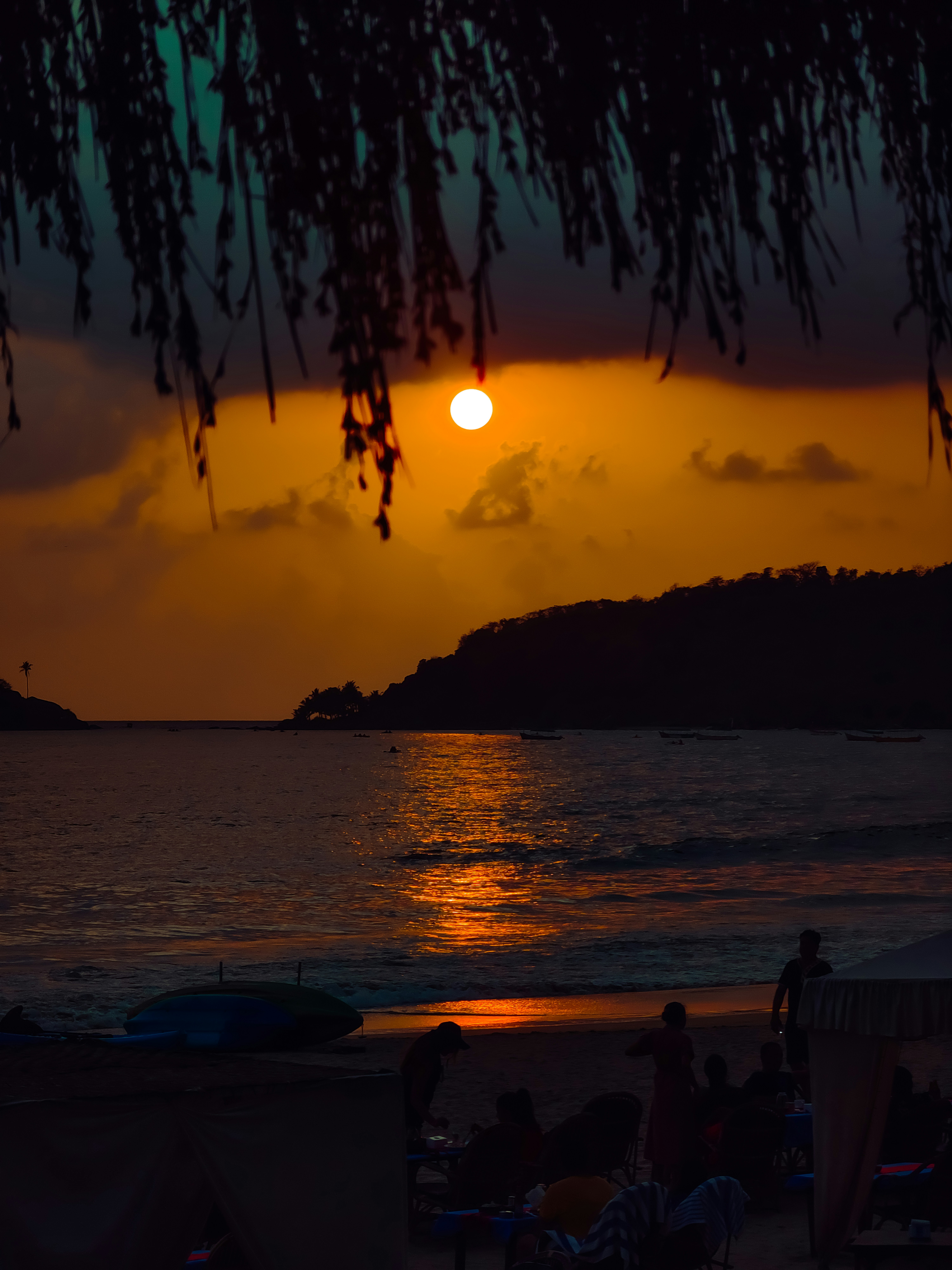 Sunset over the ocean with people on the beach