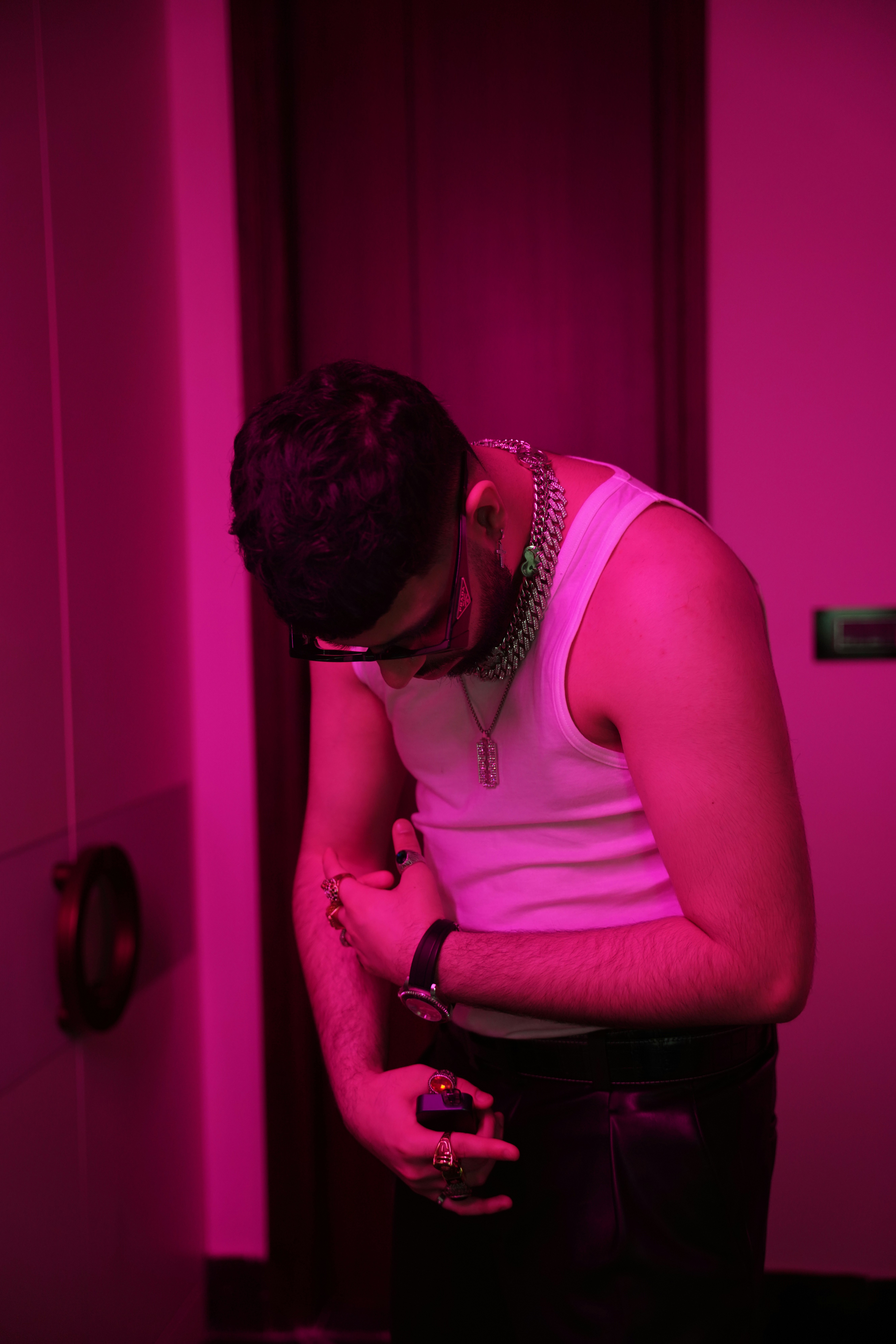Man in white tank top with jewelry bends down