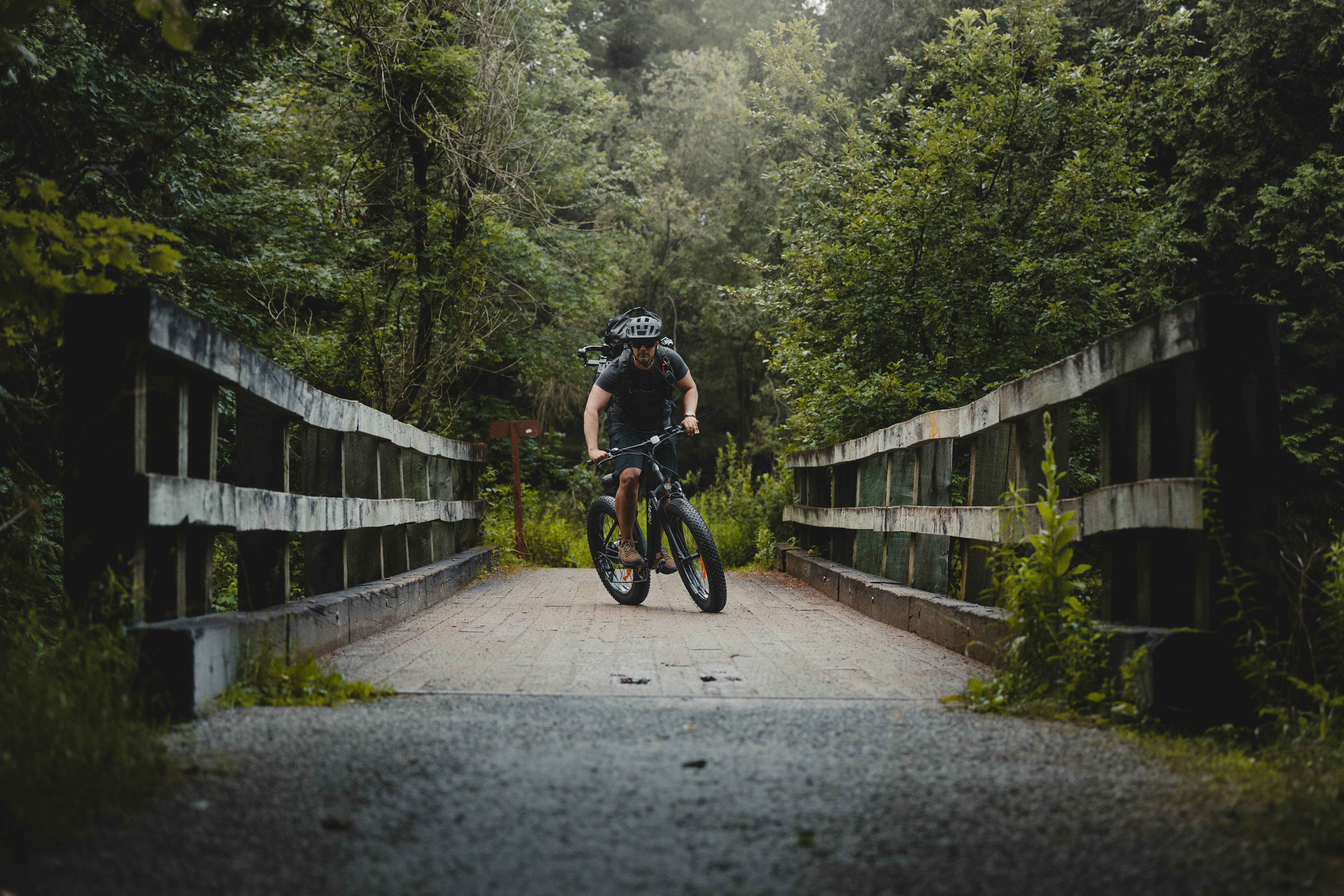 Man riding a mountain bike across a wooden bridge.
