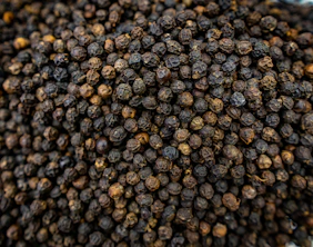 A close-up of dried black peppercorns.