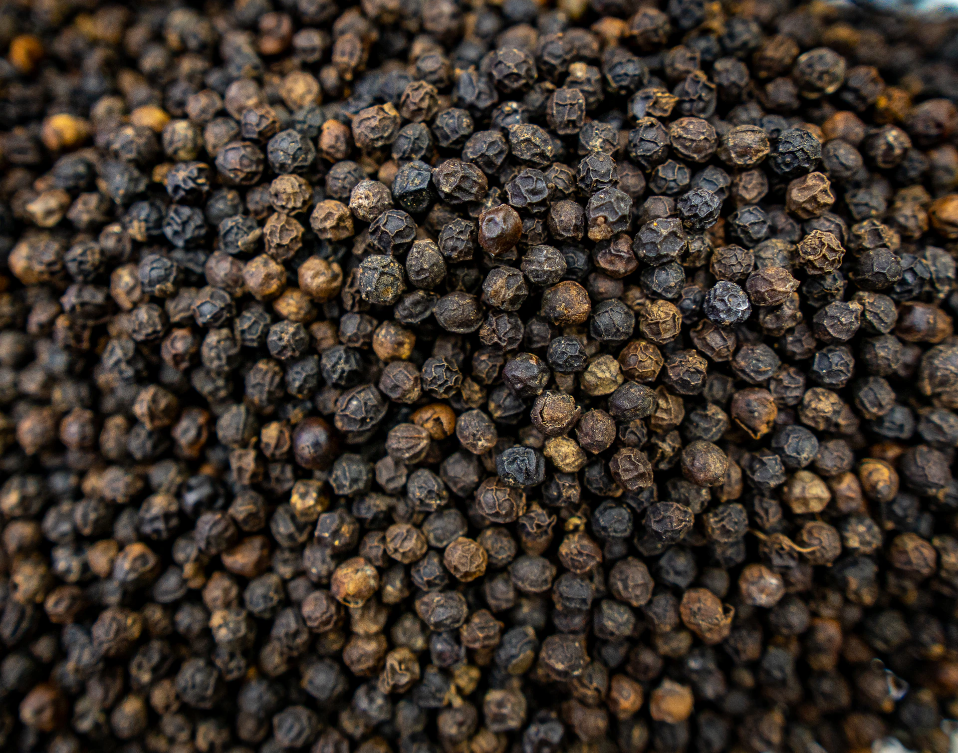 A close-up of dried black peppercorns