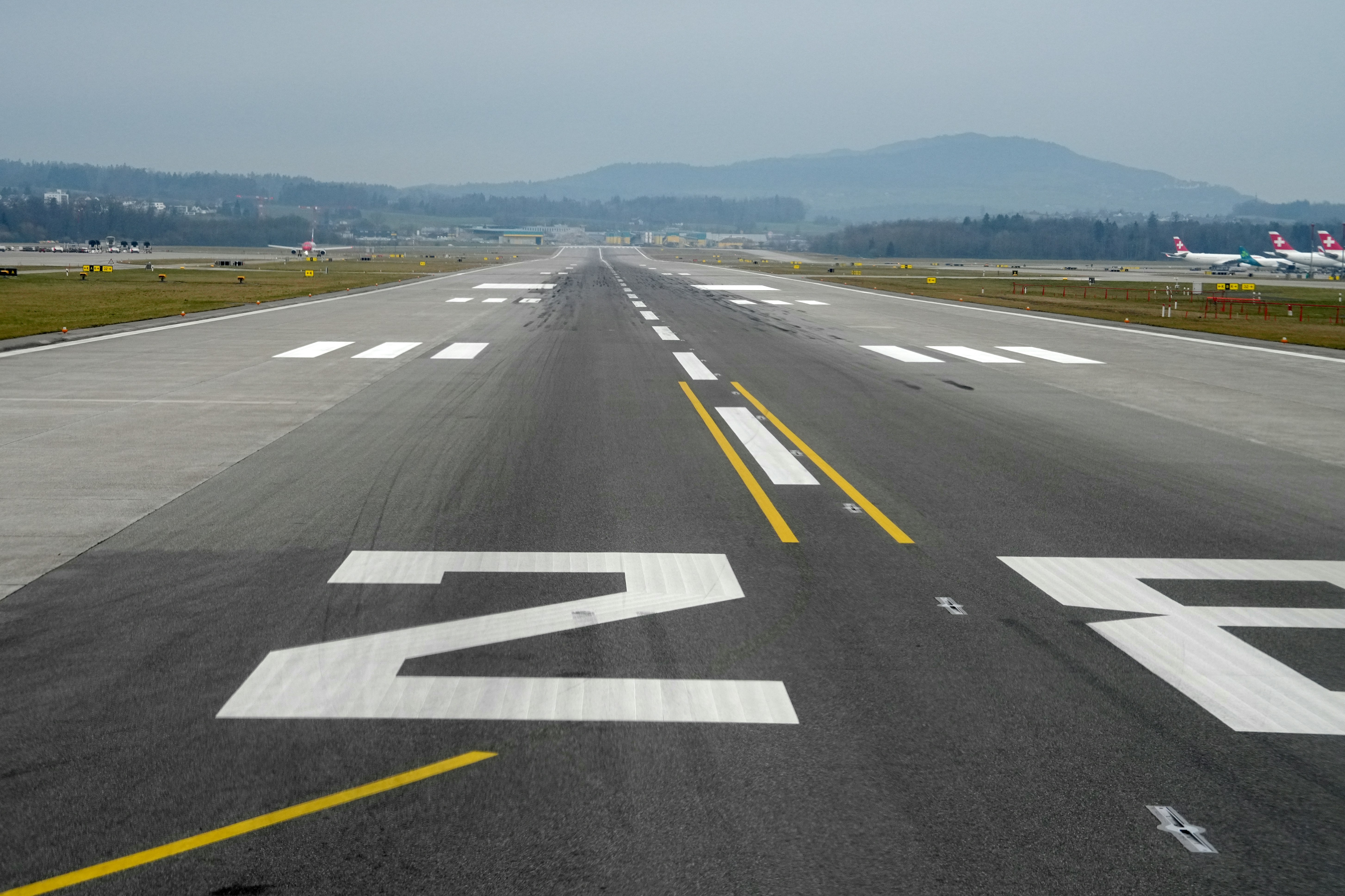 Airport runway with markings and distant airplanes