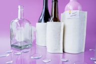 Glass bottles with white sleeves on purple background.