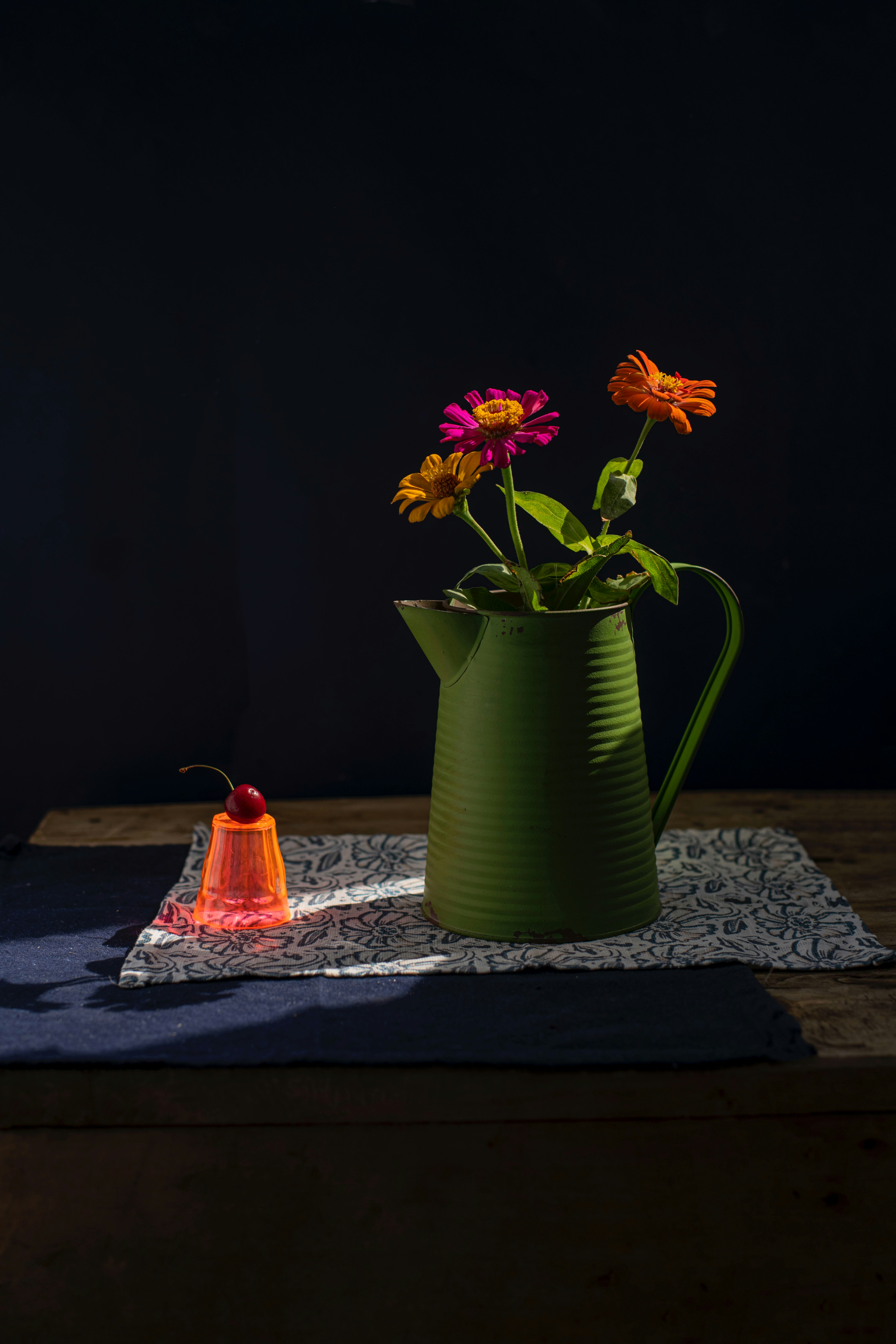 Flowers in a green pitcher with a cherry