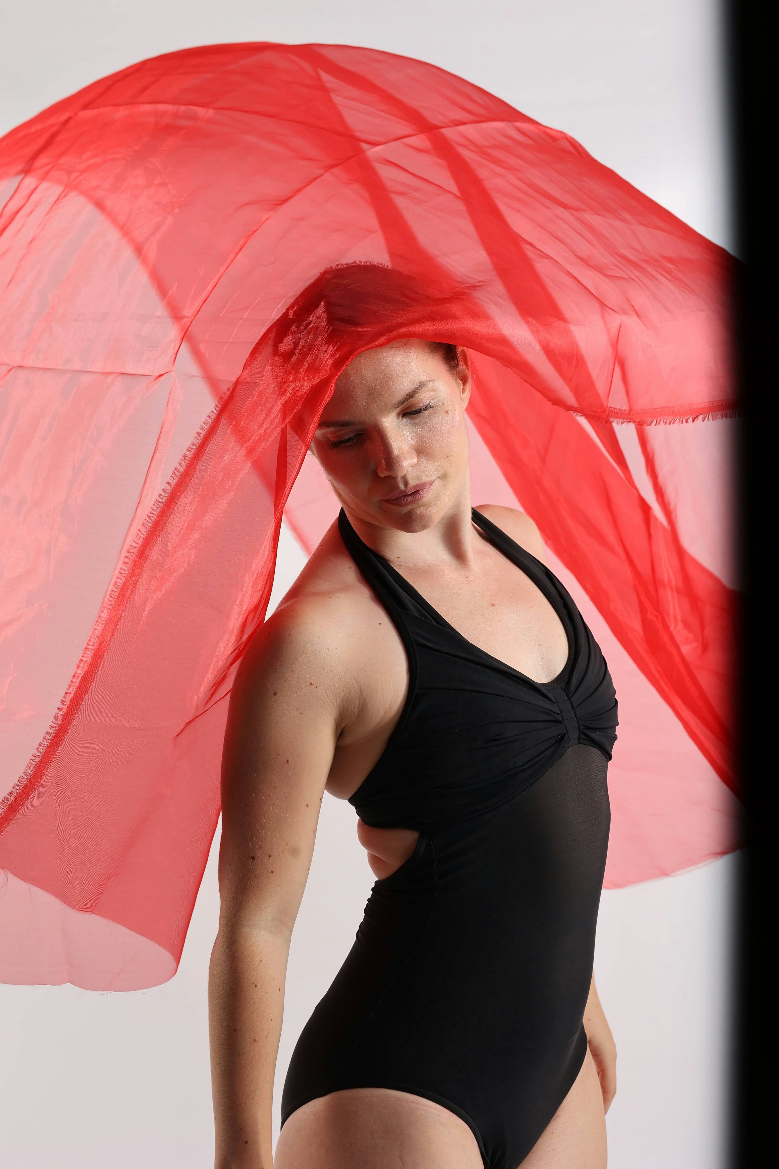 Woman in black swimsuit with flowing red fabric