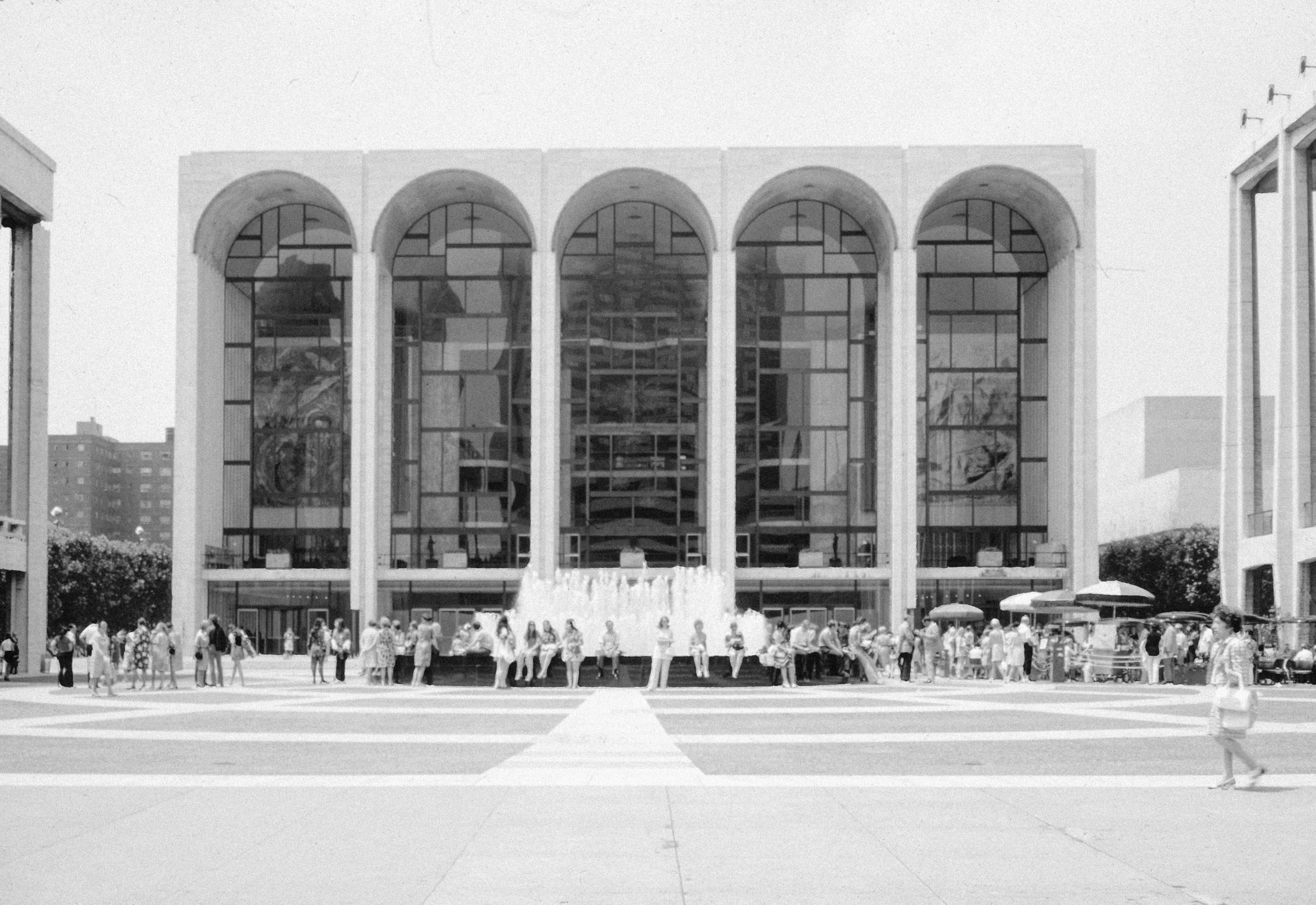 Arched windows of a modern performing arts building with visitors gathered outside in Manhattan