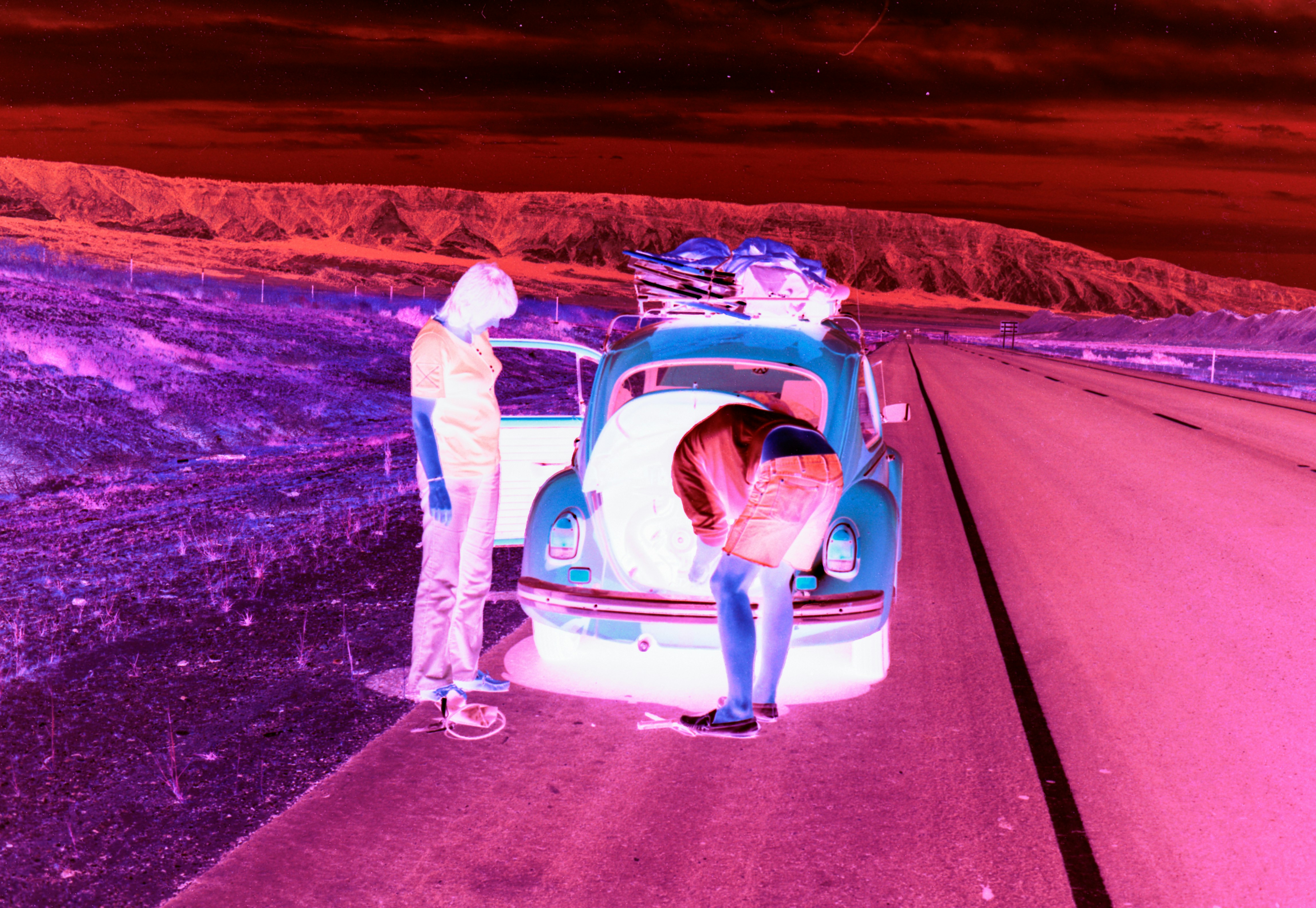 Two people loading gear into a vintage car.