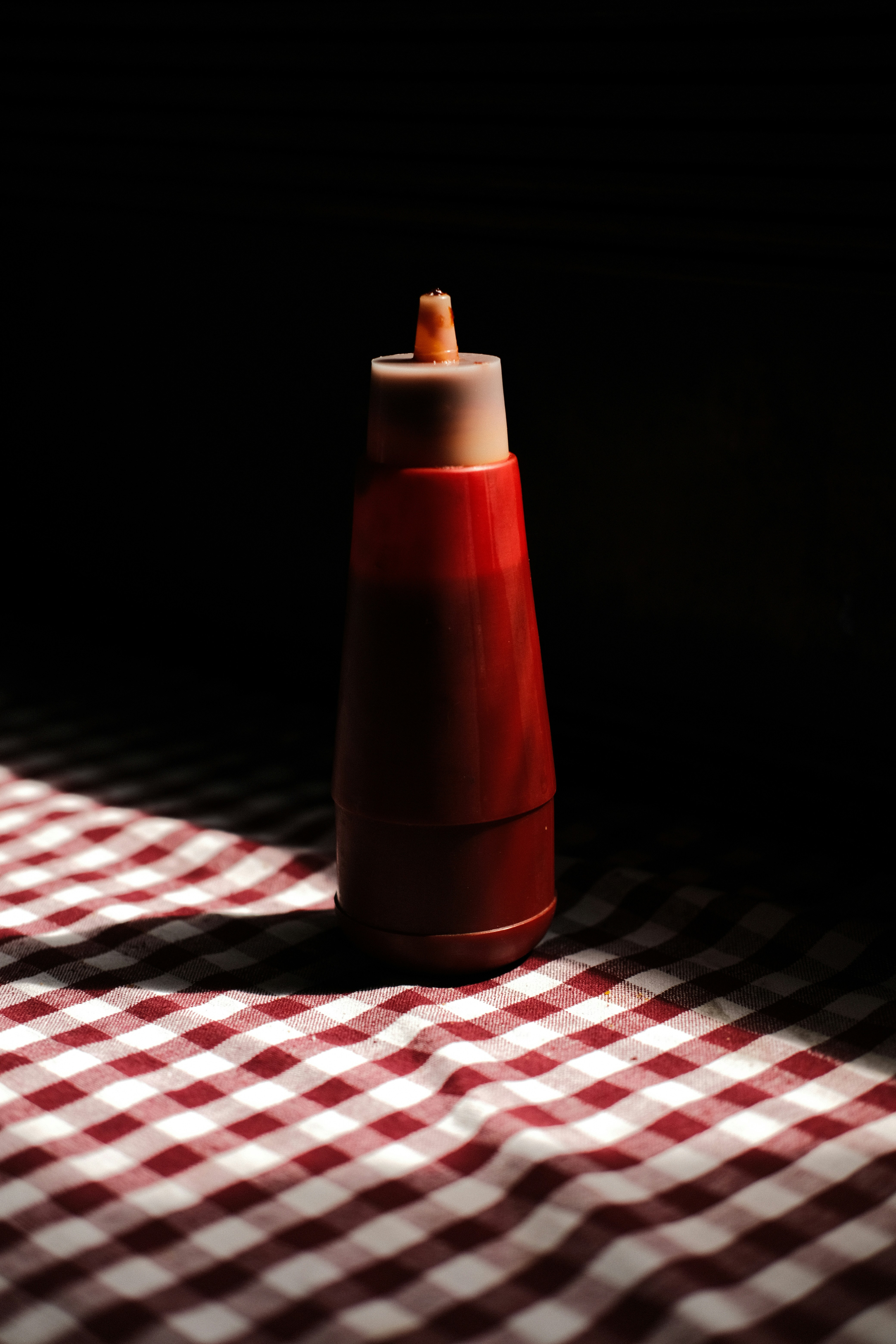 Eine rote Quetschflasche auf einer karierten Tischdecke