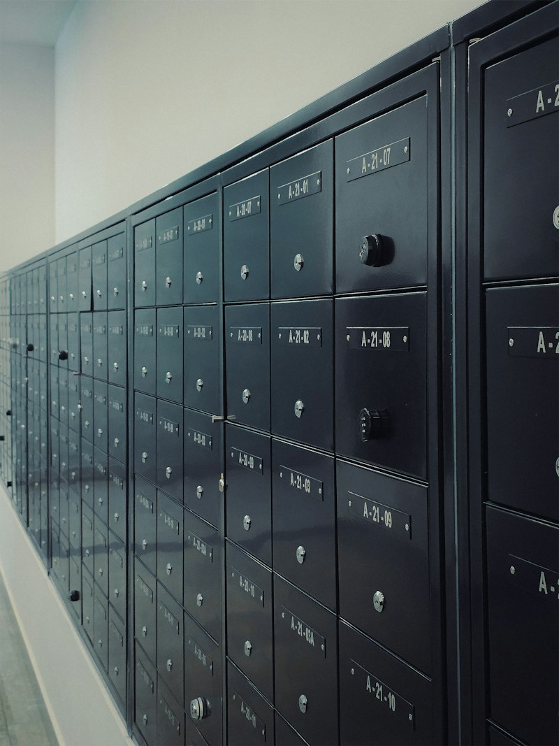 A row of dark metal mailboxes with numbered doors