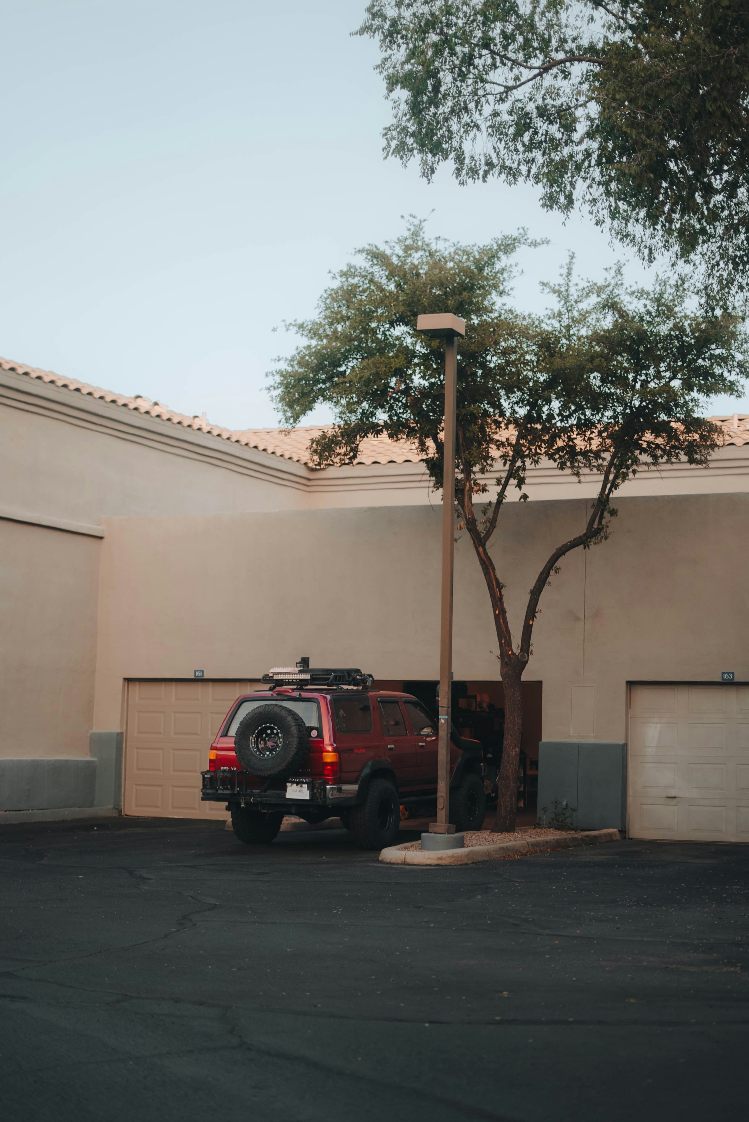 Red suv parked next to a tree and garage