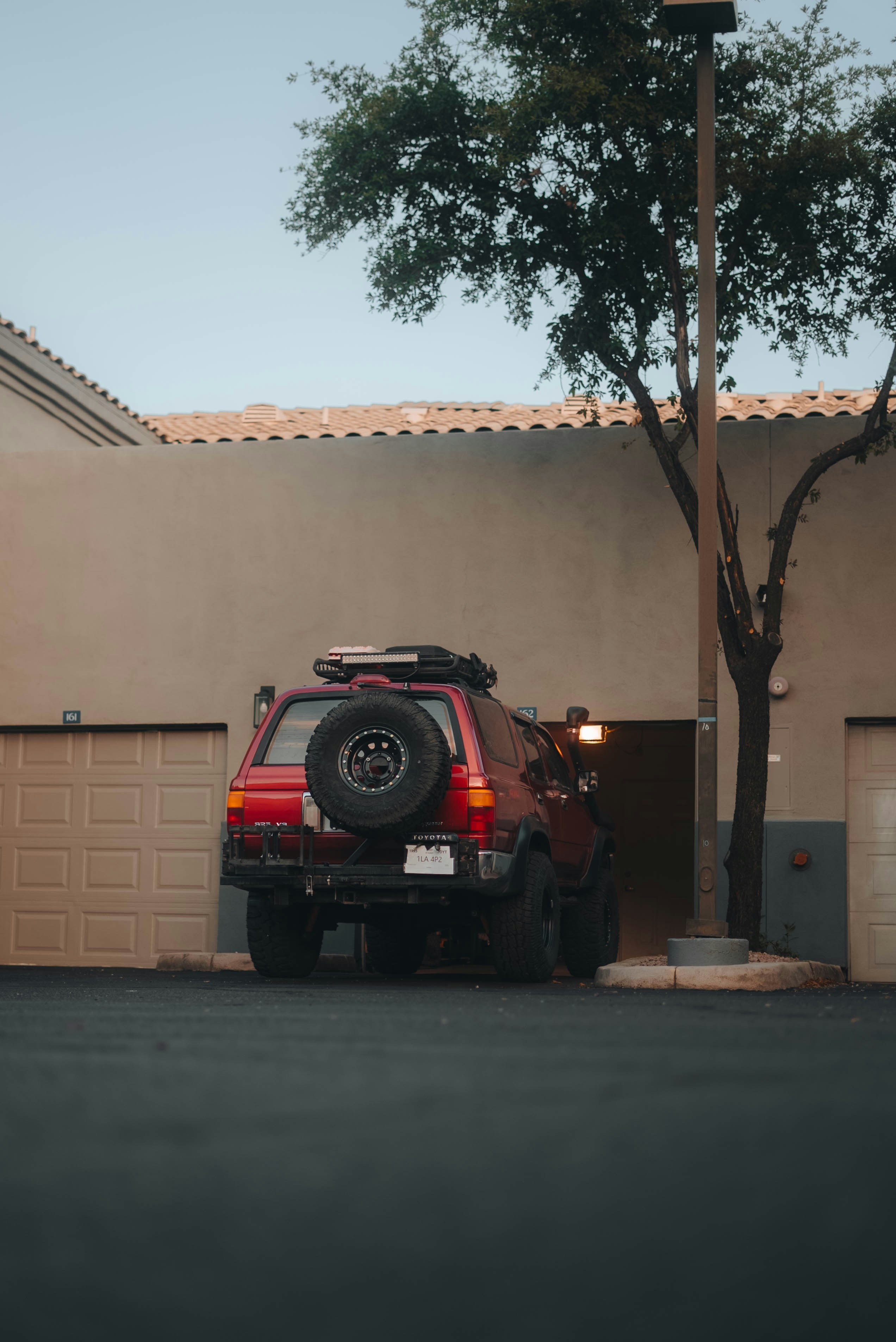 Red suv with spare tire parked near garages