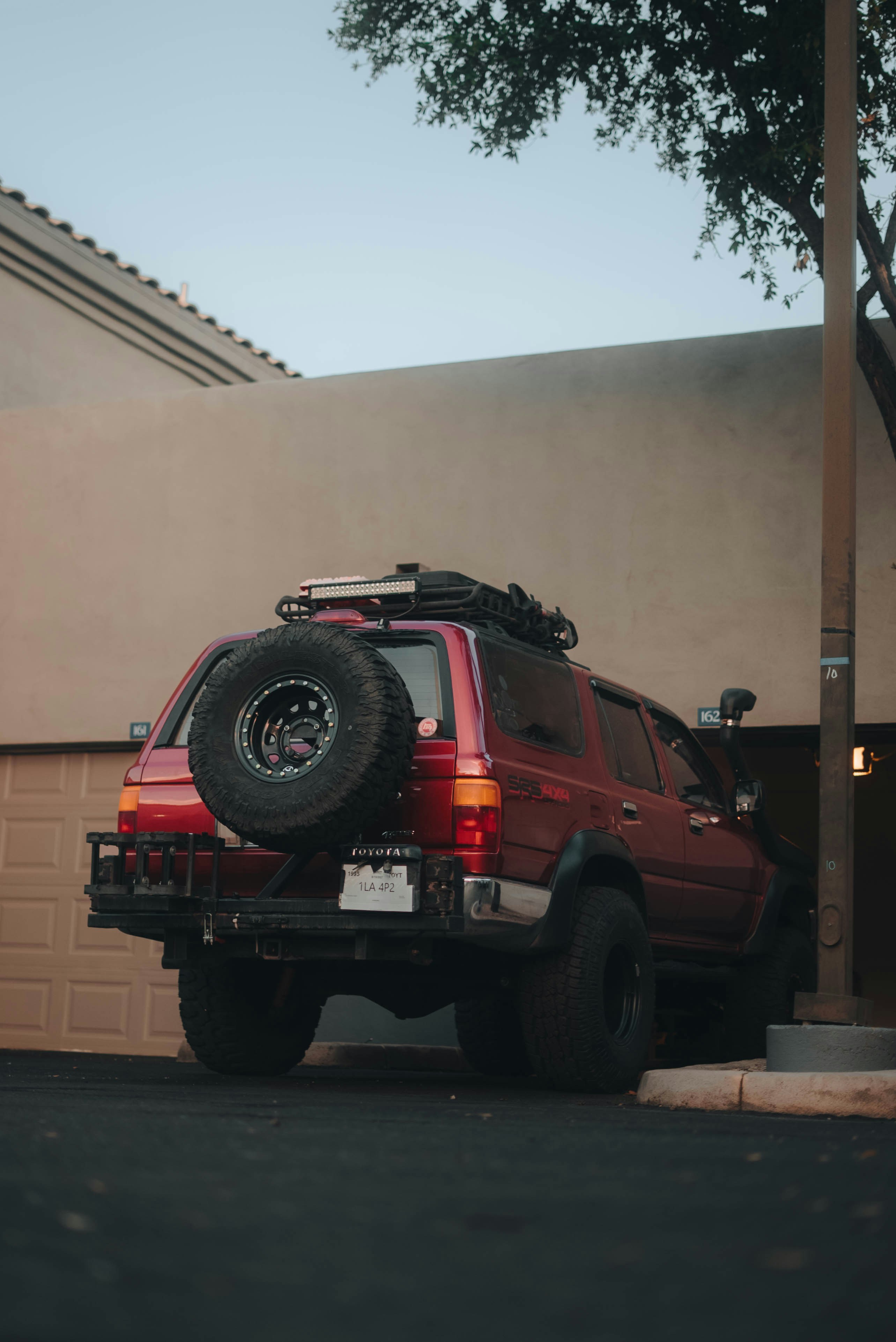 Red suv with spare tire parked near garage