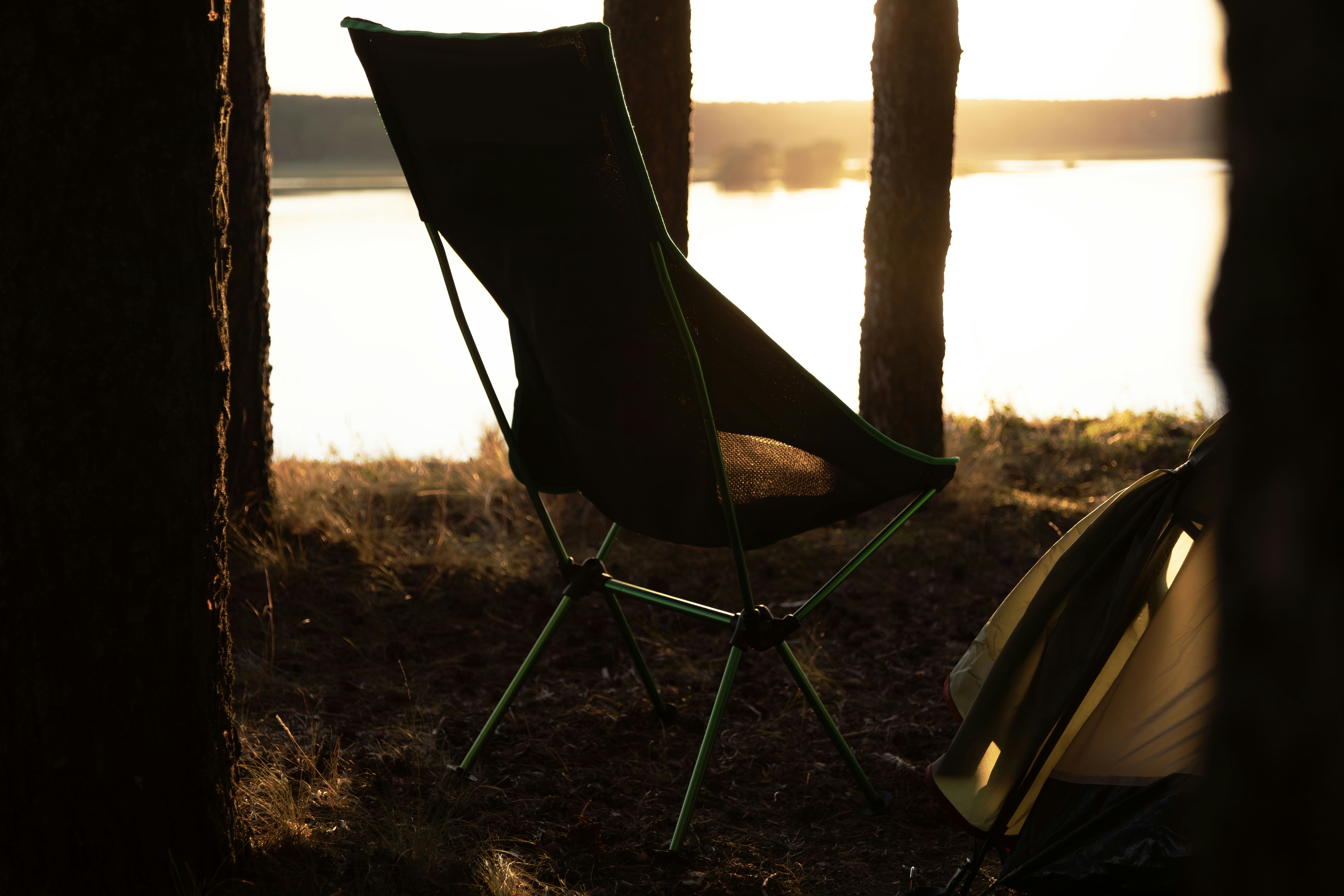 Camp chairs by lake at sunset