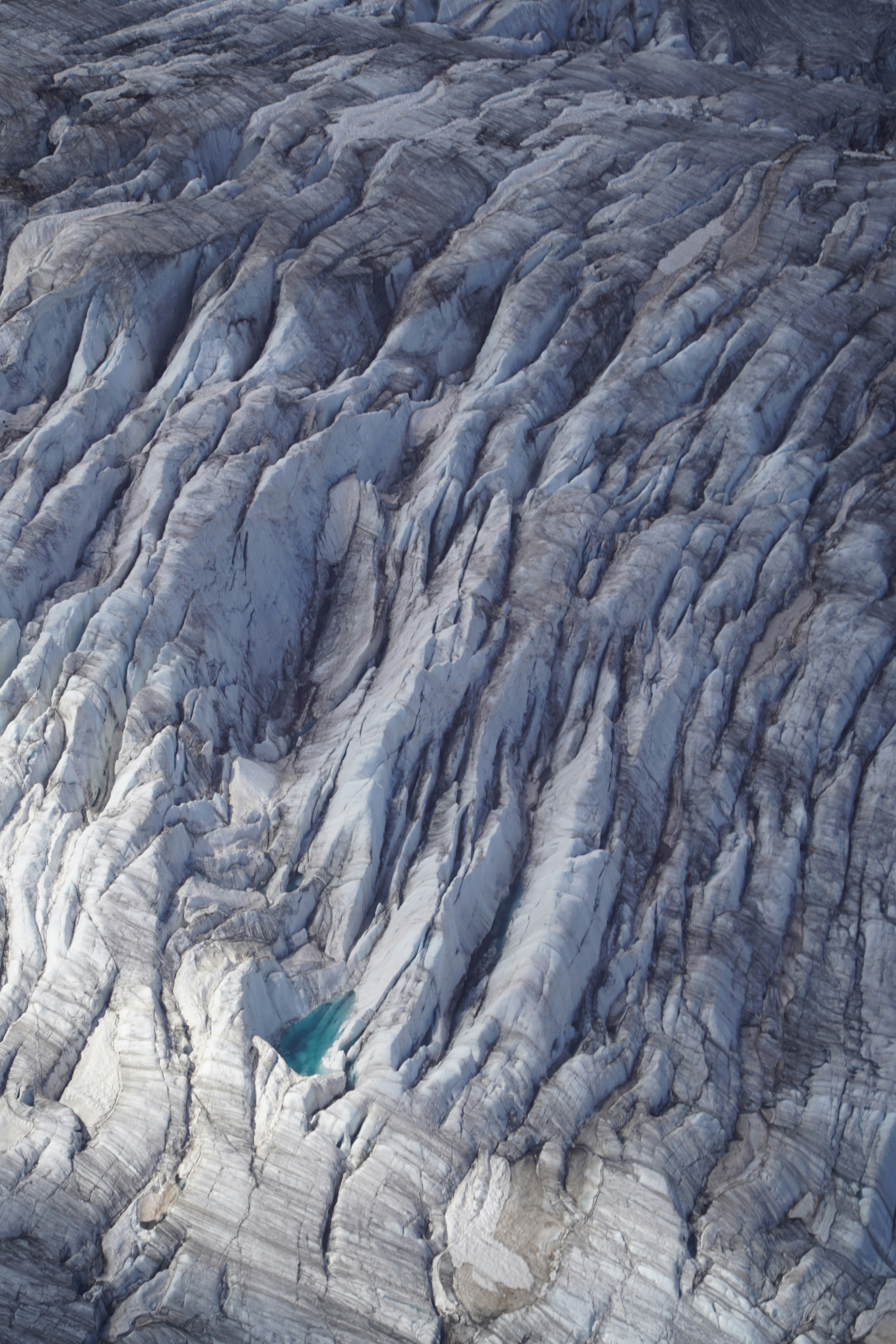 Textured glacier surface with a small blue pool.