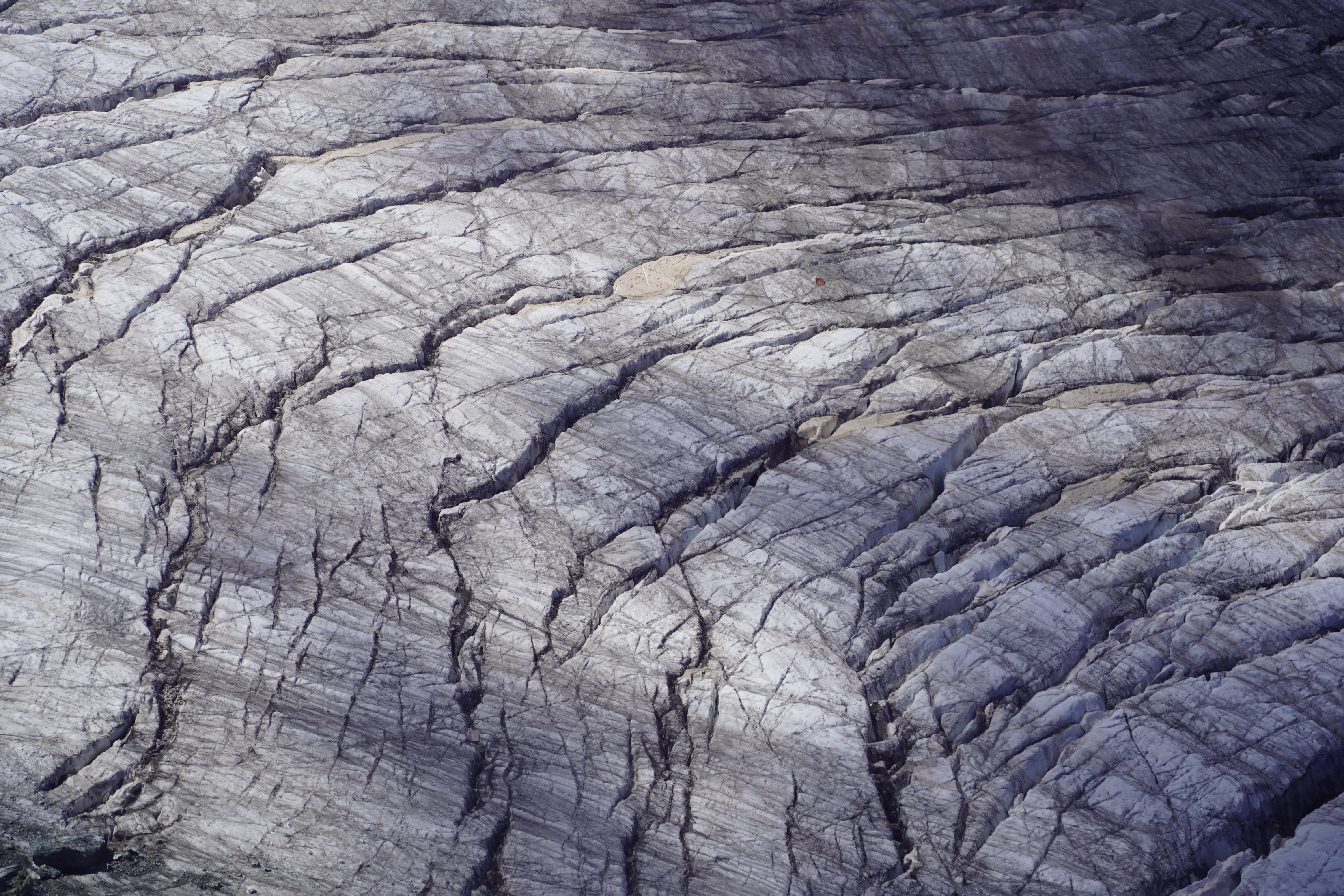 Cracked glacial ice with dark debris patterns.
