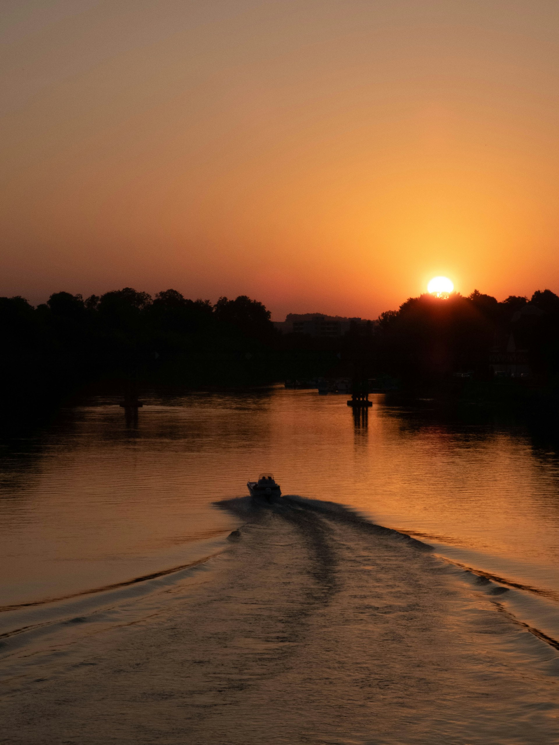 Boat leaving wake on river at sunset