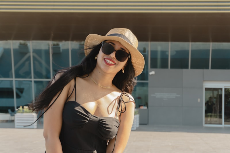 Woman in hat and sunglasses smiles outdoors