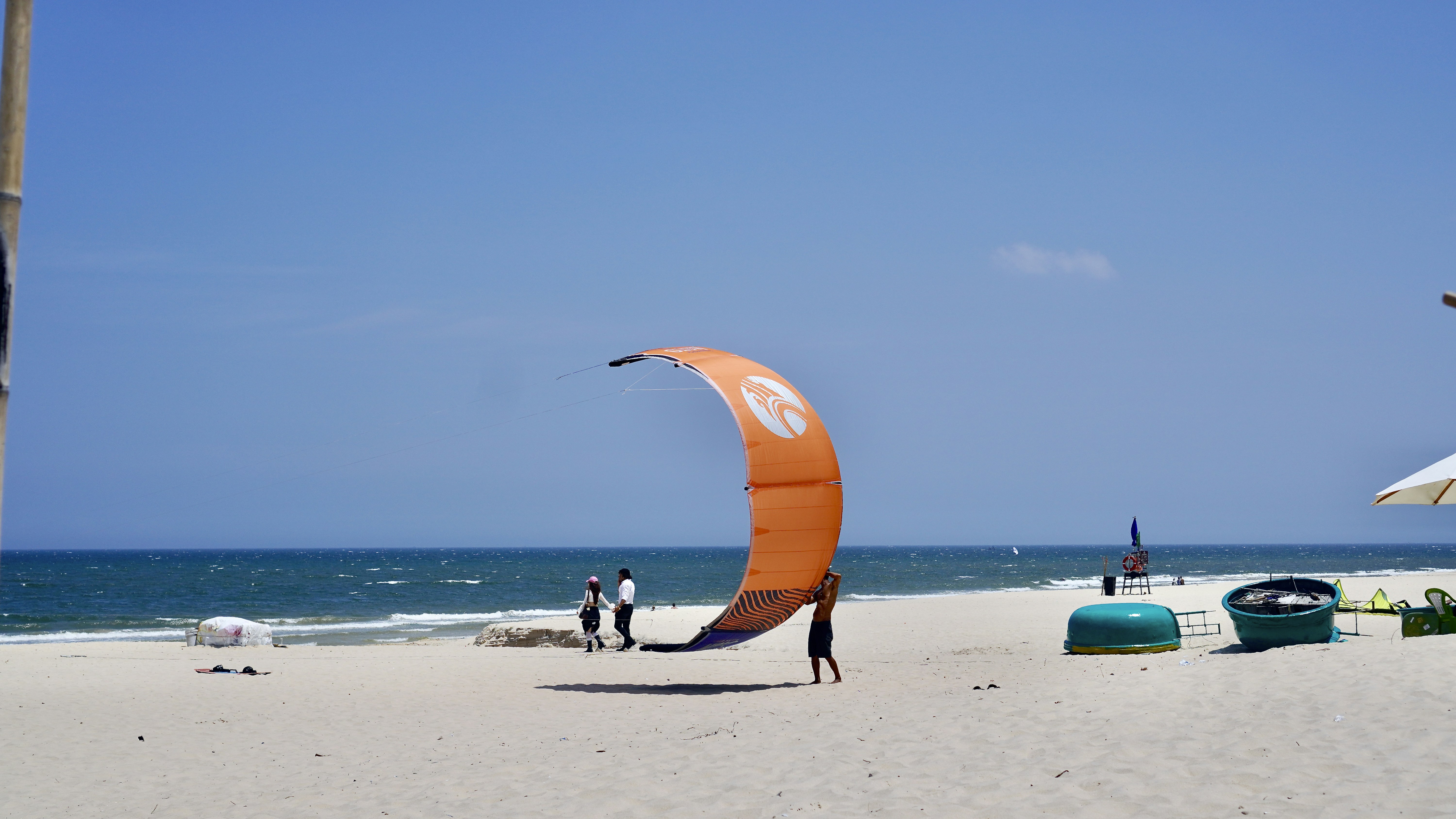 Orange kite on a sandy beach near the ocean.