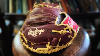 A maroon baseball catcher's mitt rests on a chair.
