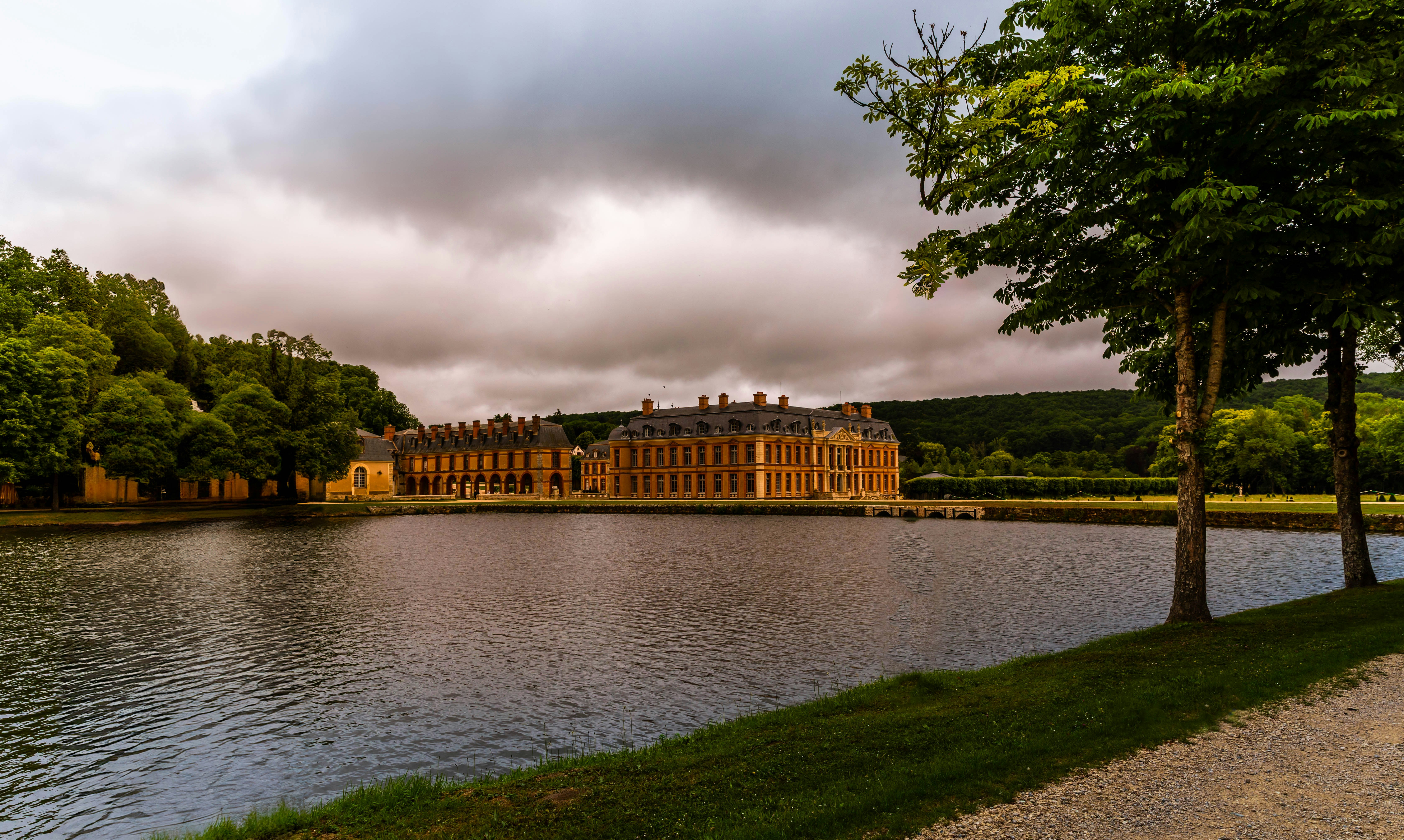 Grand building beside a calm lake with trees