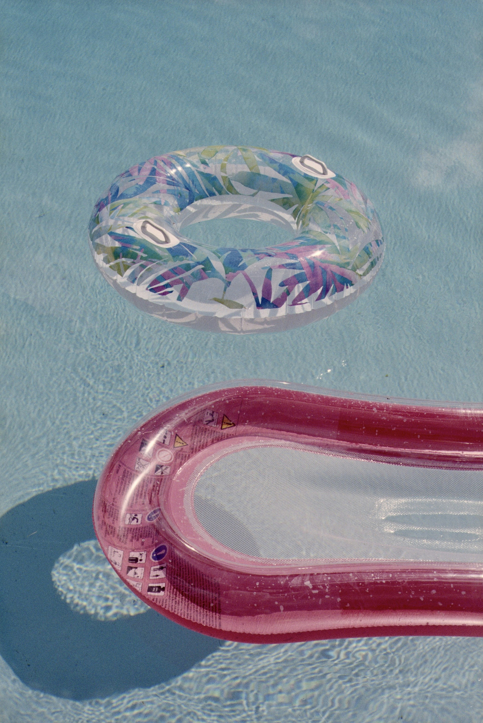 Two inflatable pool floats on clear blue water
