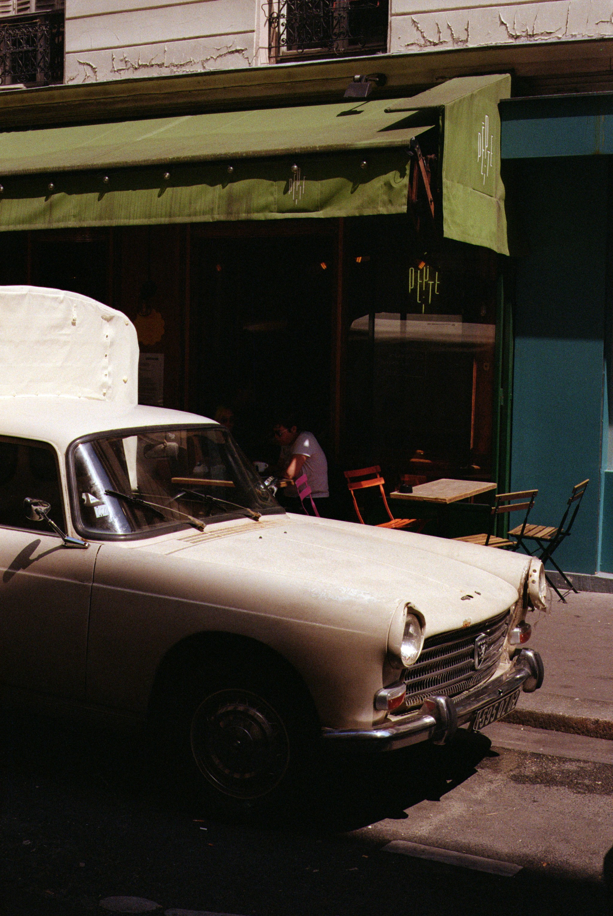 Vintage car parked outside a cafe with green awning