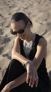 Woman in black dress with statement necklace on sand