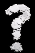 Torn paper pieces form a question mark on black background