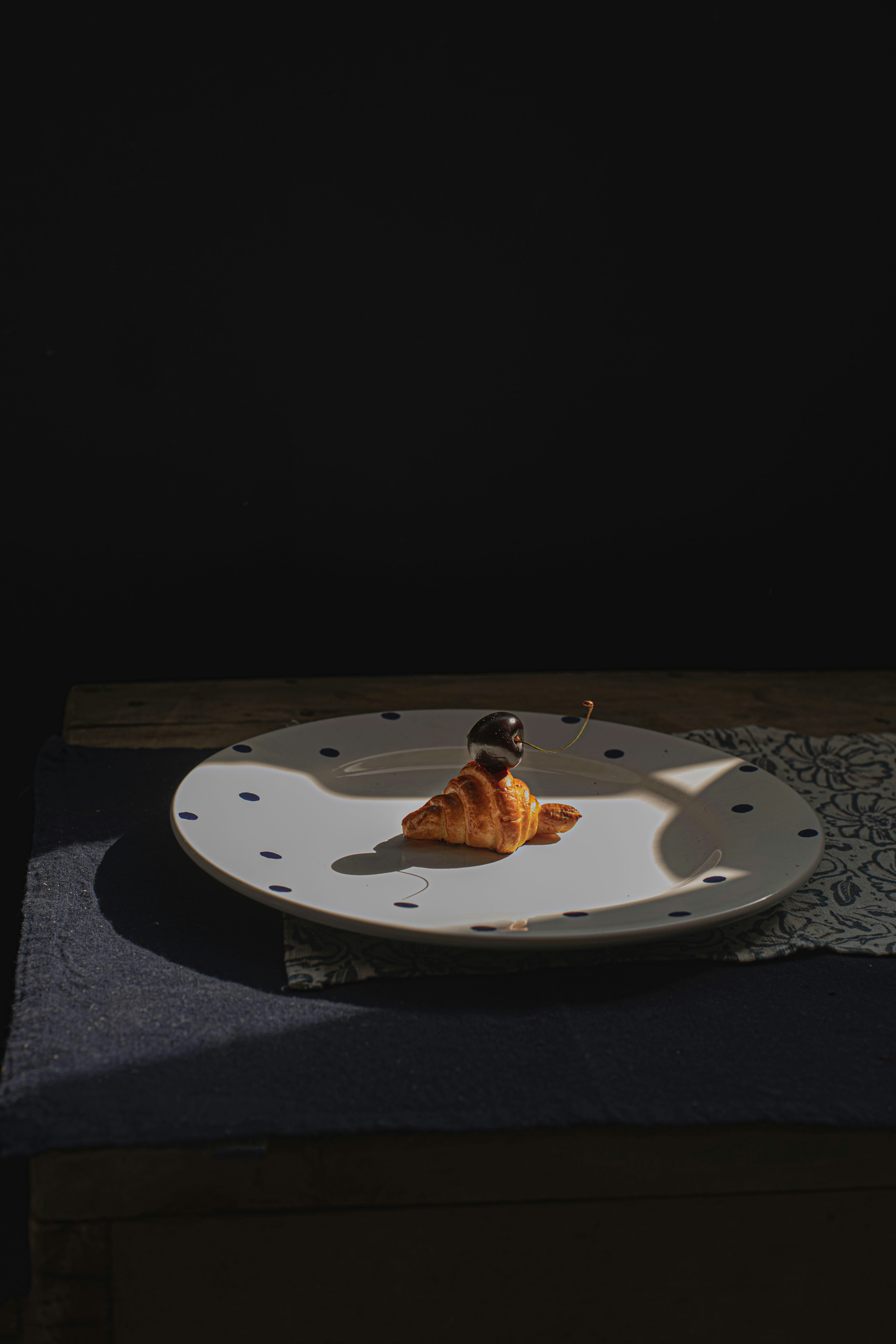 Croissant with blueberries on a polka dot plate.