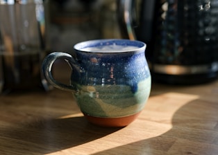 A colorful ceramic mug filled with a beverage.