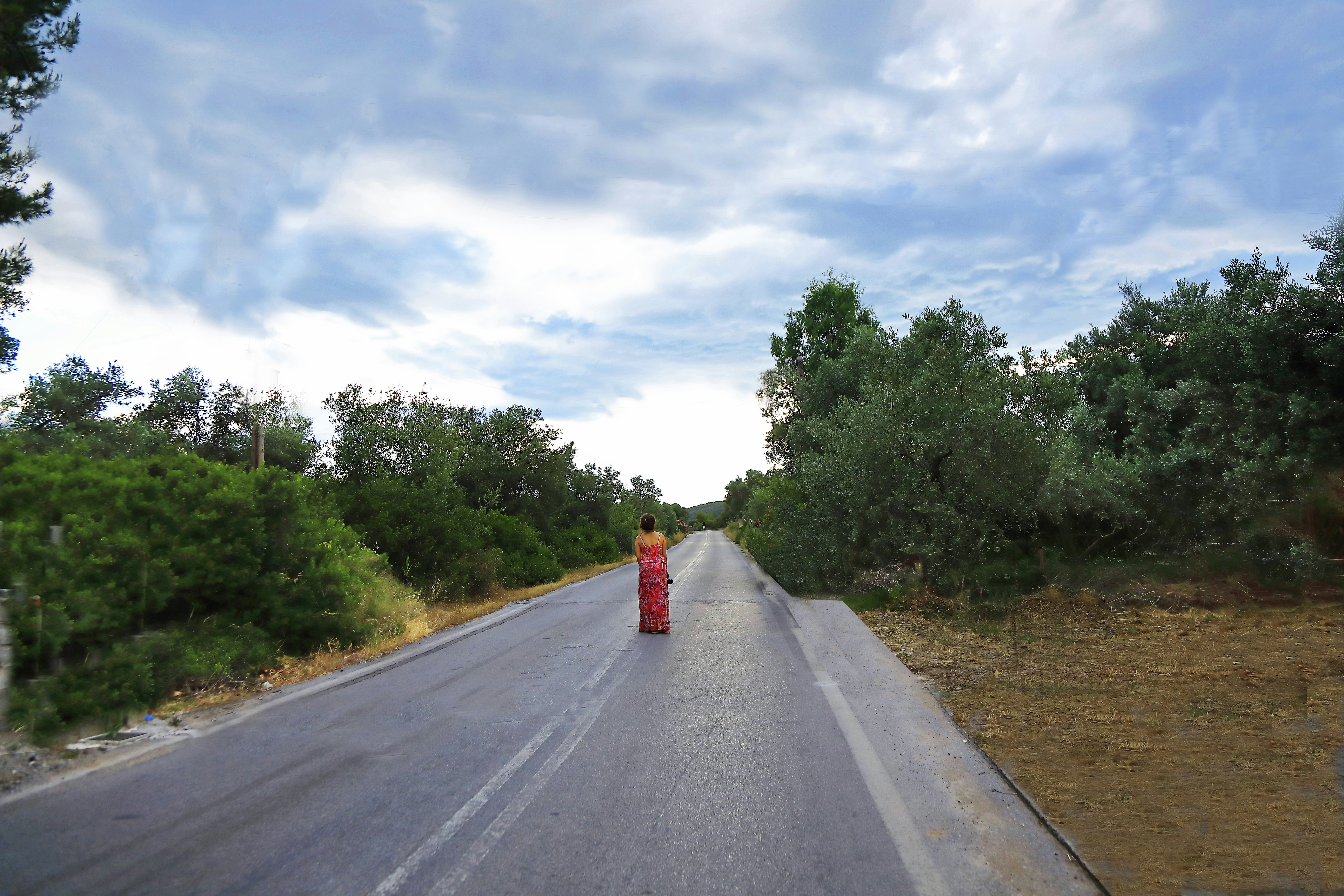 Woman in orange dress walks down a country road