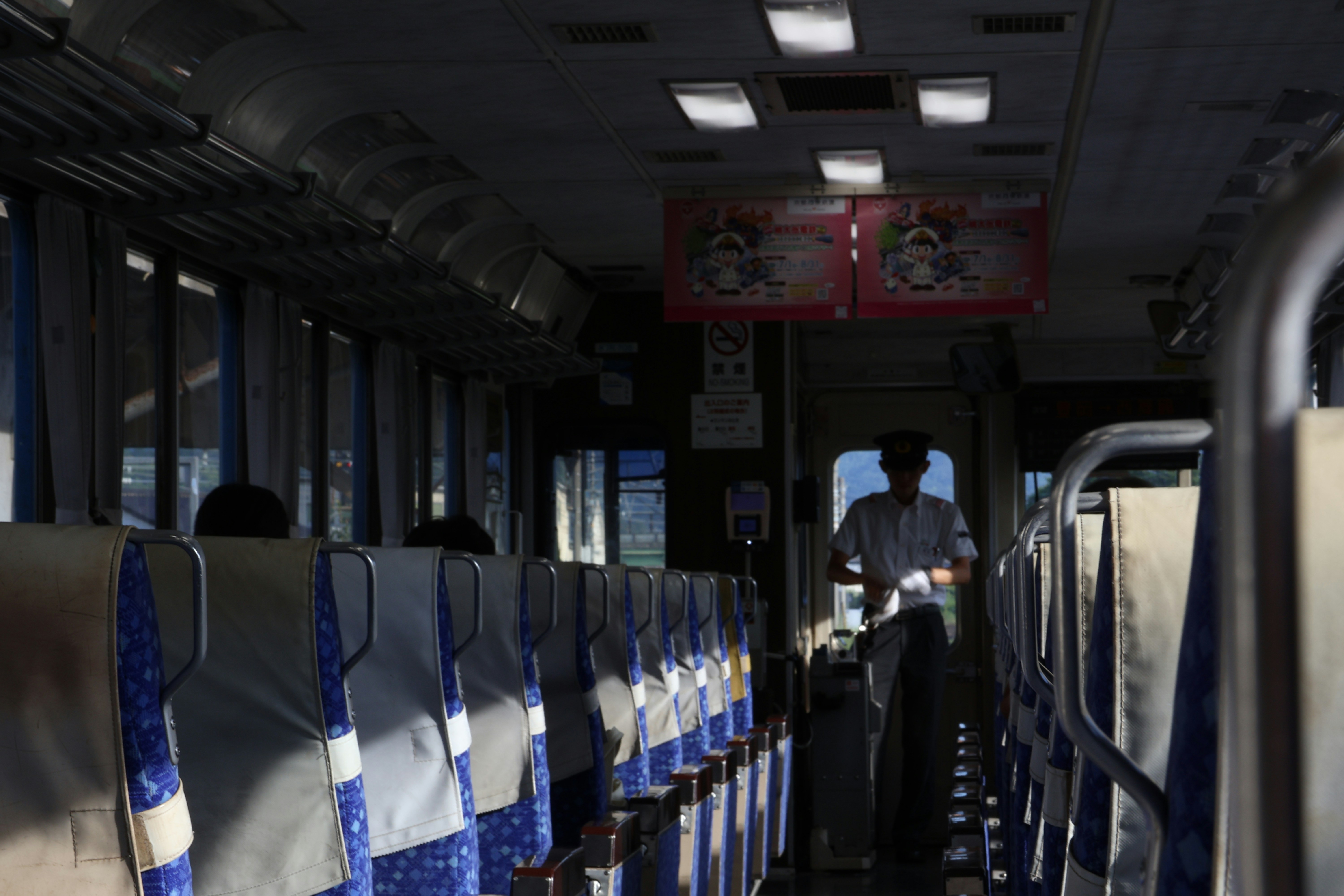 Man walking down empty train aisle with seats.