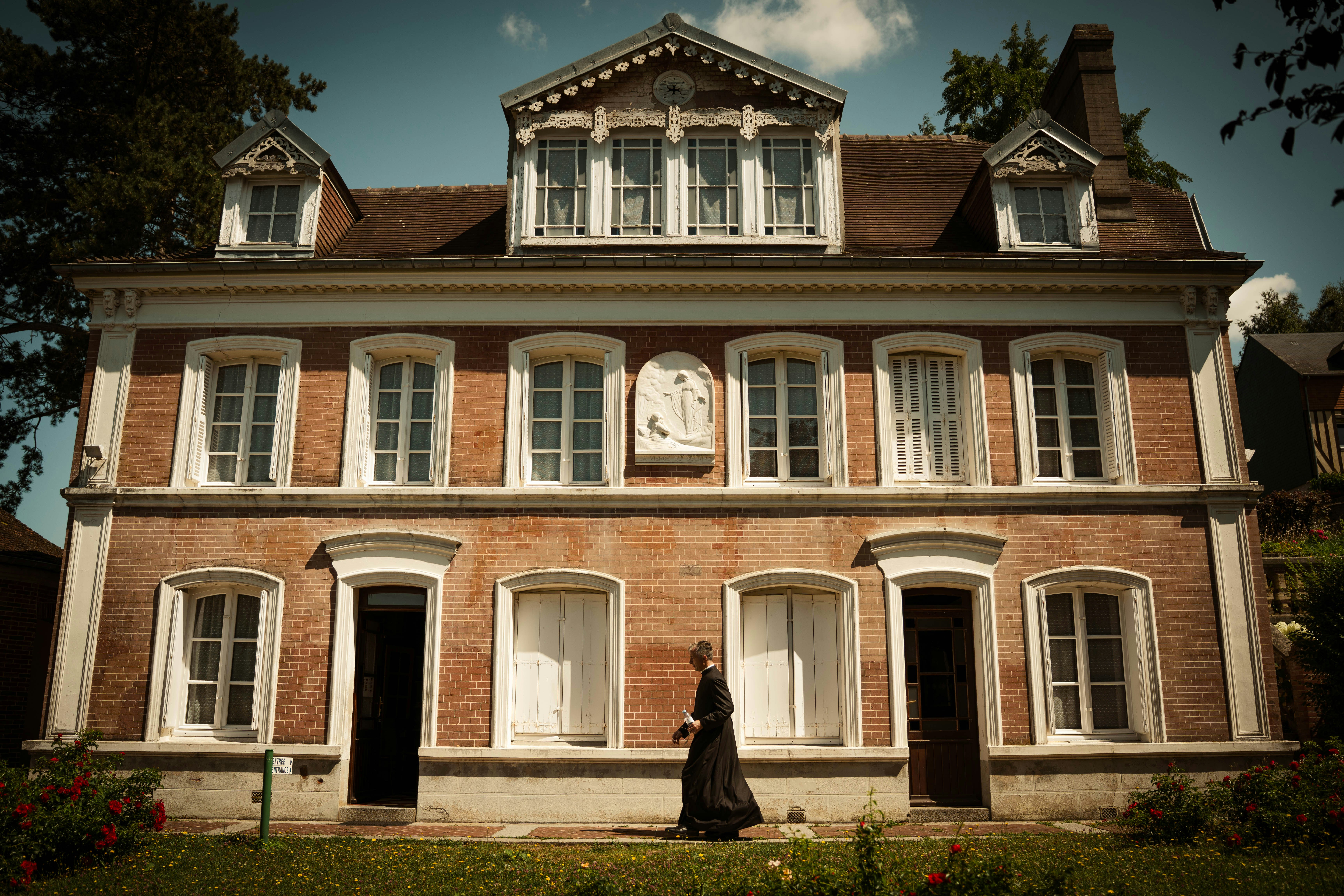 Woman in vintage dress walks in front of old brick house