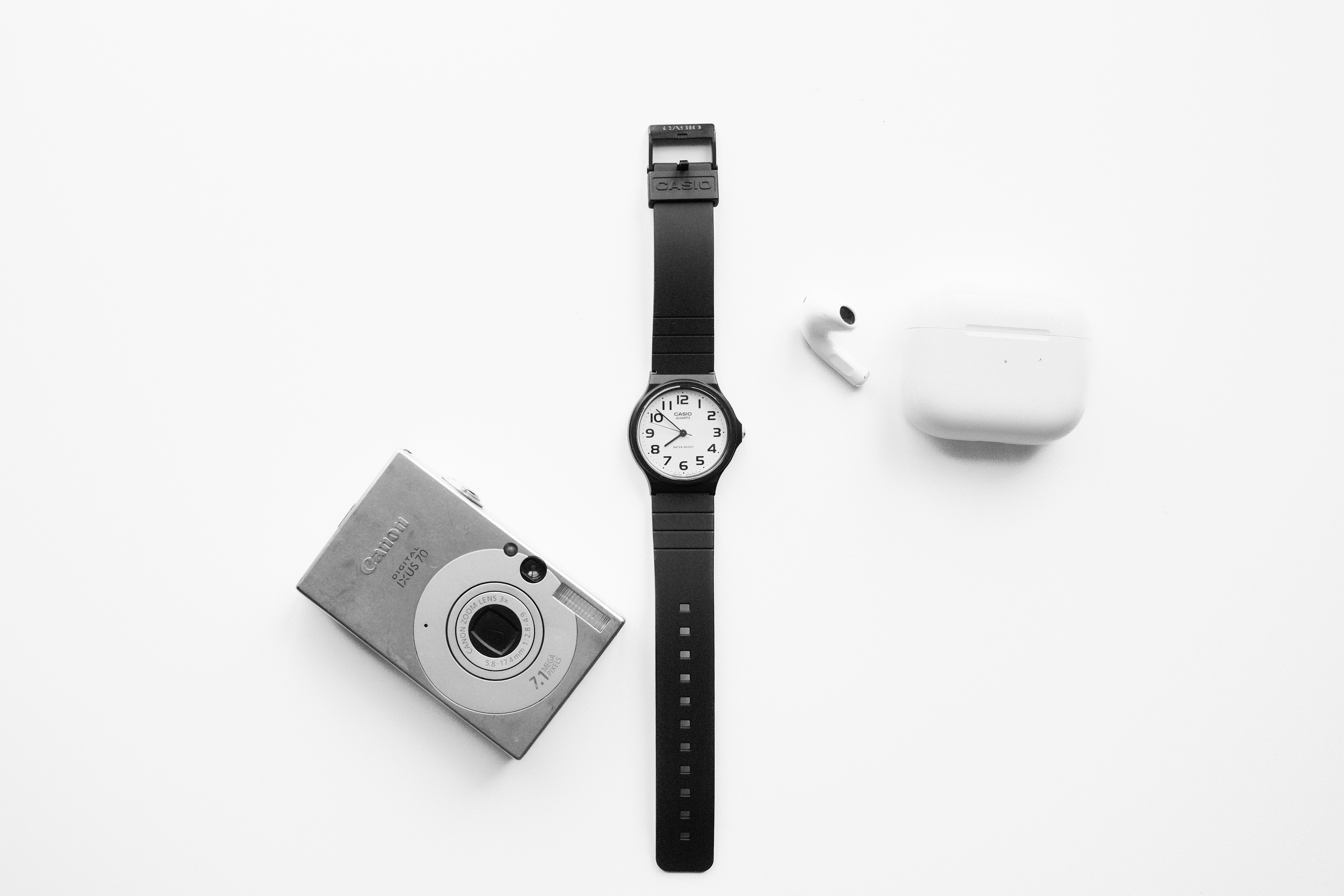 Camera, watch, and wireless earbuds on white background