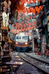 Train approaching narrow street lined with cafes and flags