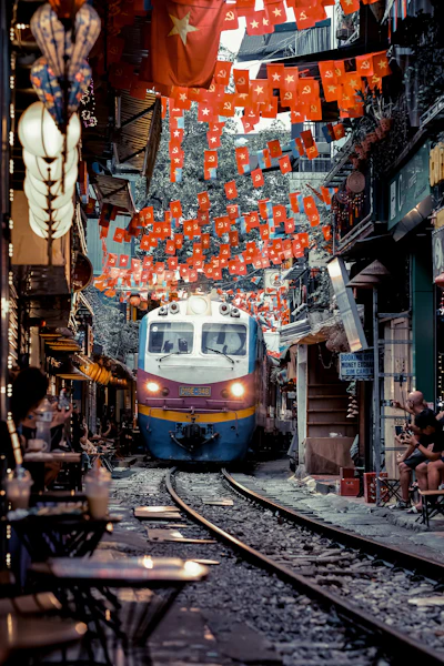 A train passing down the narrow tracks of Hanoi's Train Street, cafes lining both sides