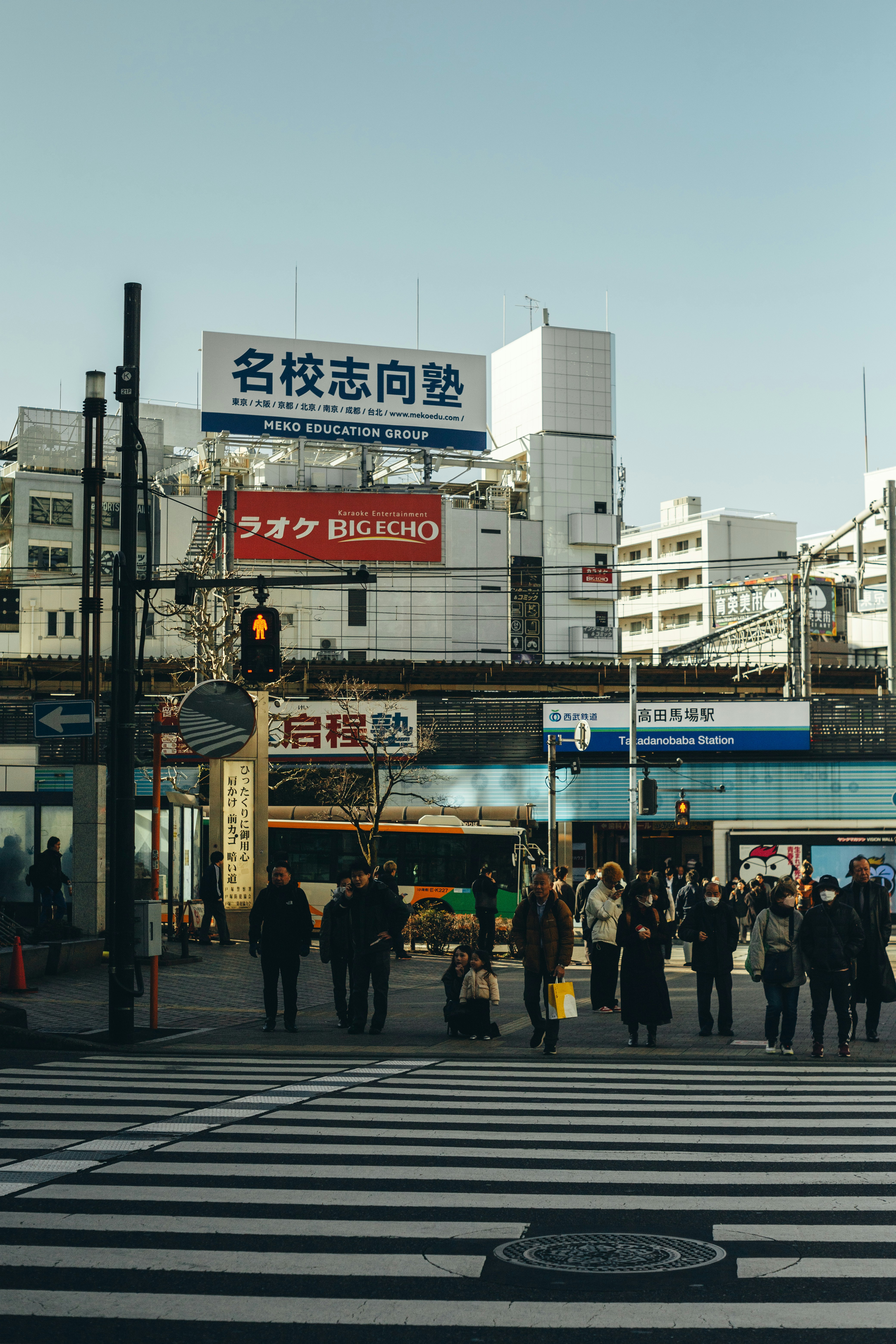 Des gens traversent une rue animée devant des immeubles.